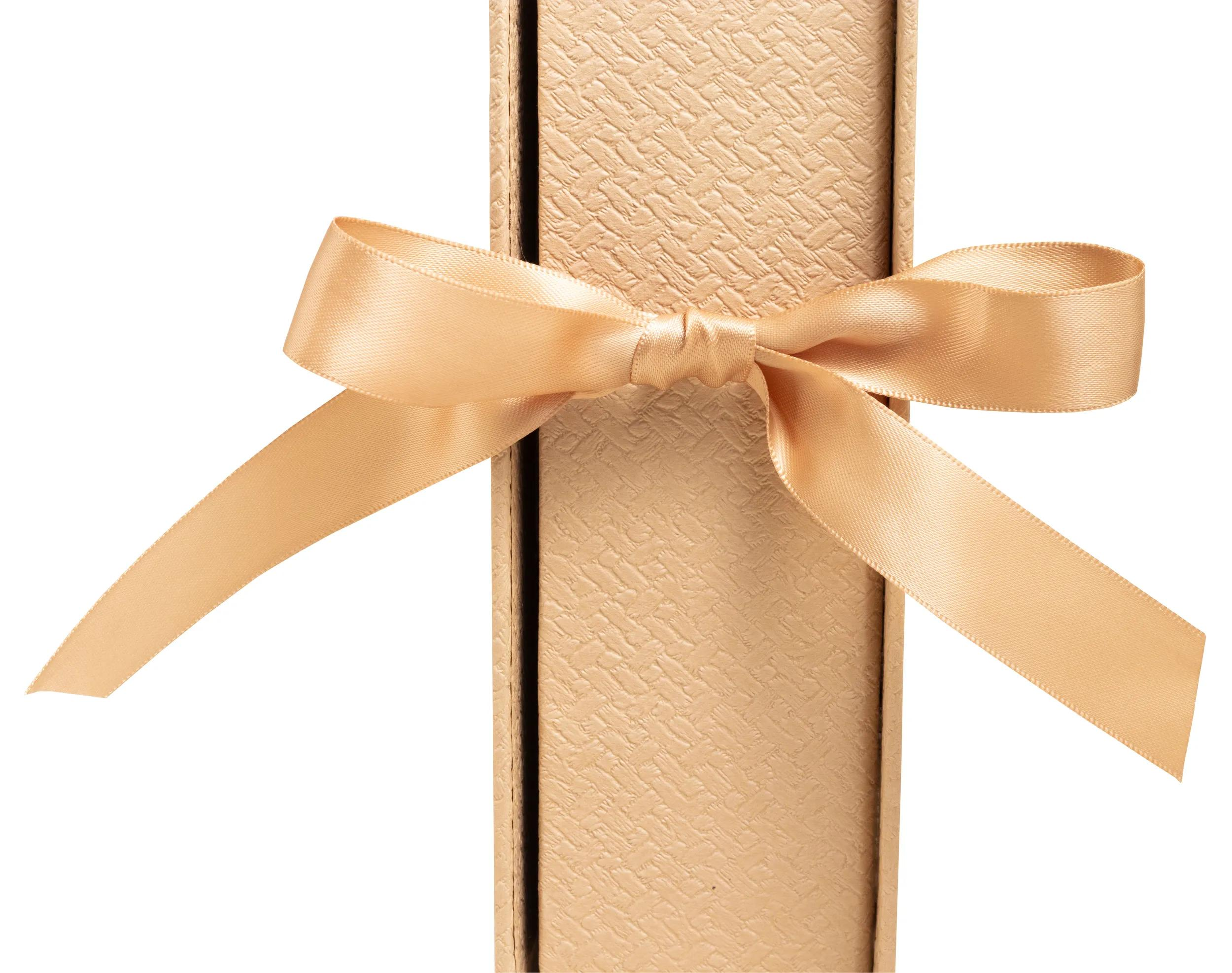 Una cinta dorada ata una caja de regalo estrecha y texturizada.