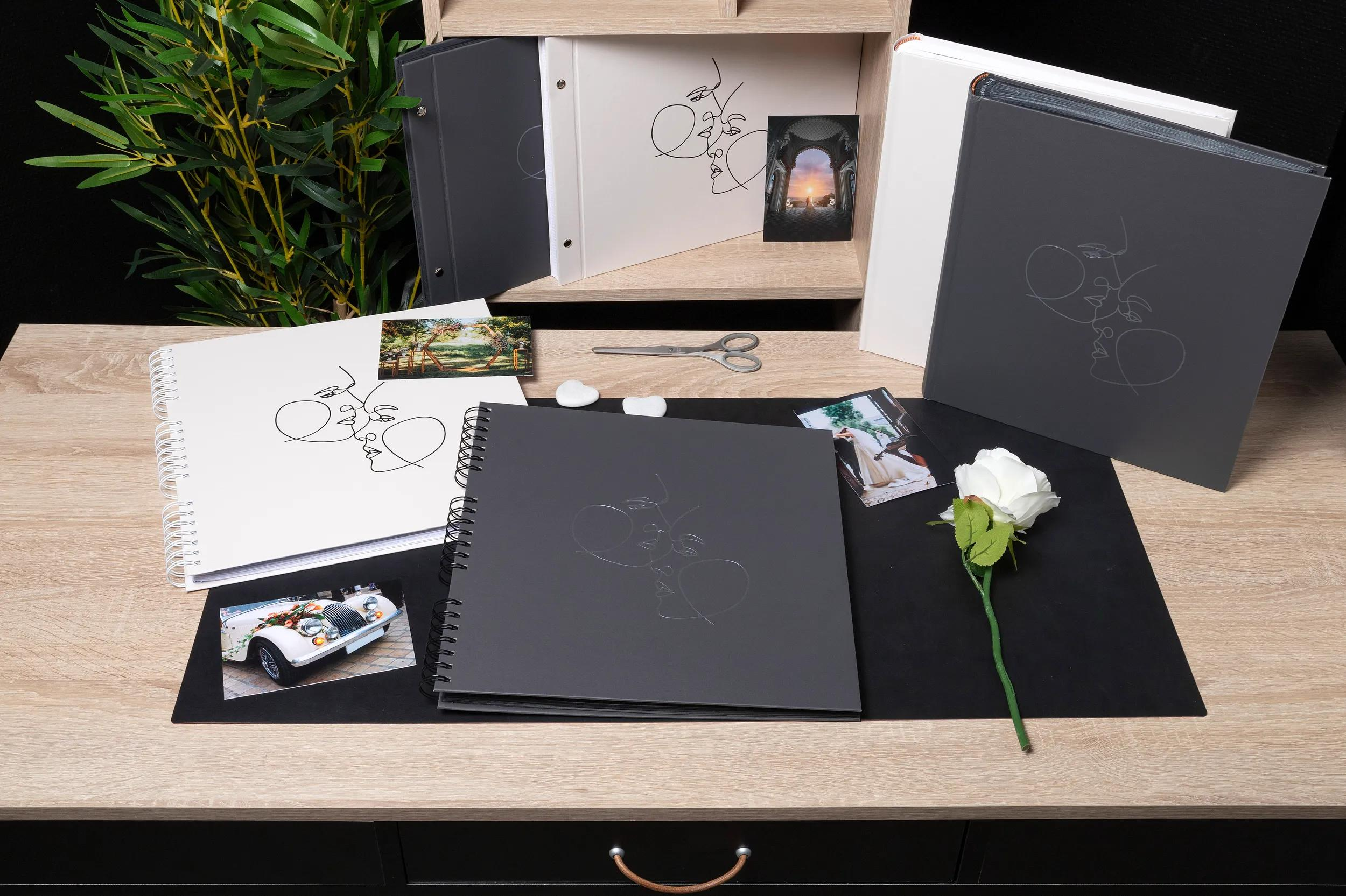 Álbumes de fotos abiertos con contornos de rostros, fotos y una rosa blanca sobre mesa.