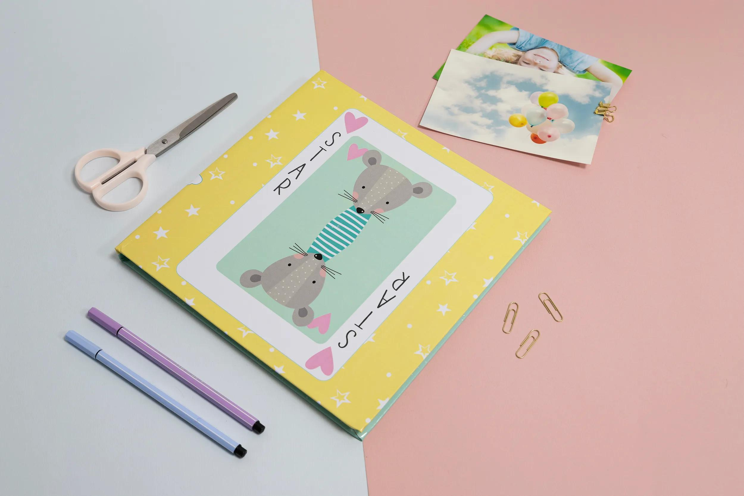 Tijeras, bolígrafos, cuaderno con ratones y fotos de globos y un niño.