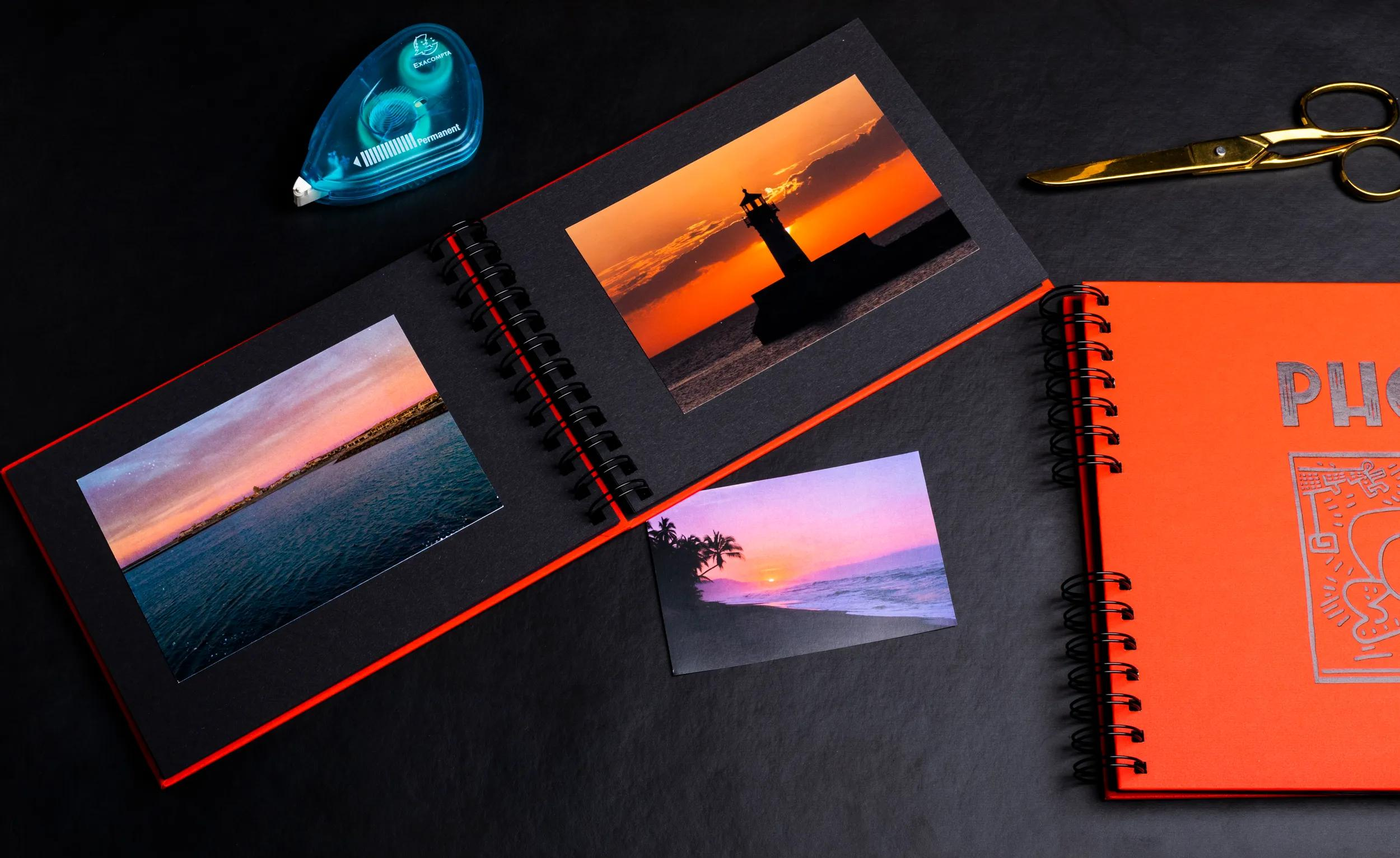 Un álbum de fotos abierto con tres imágenes, tijeras y cinta sobre fondo negro.