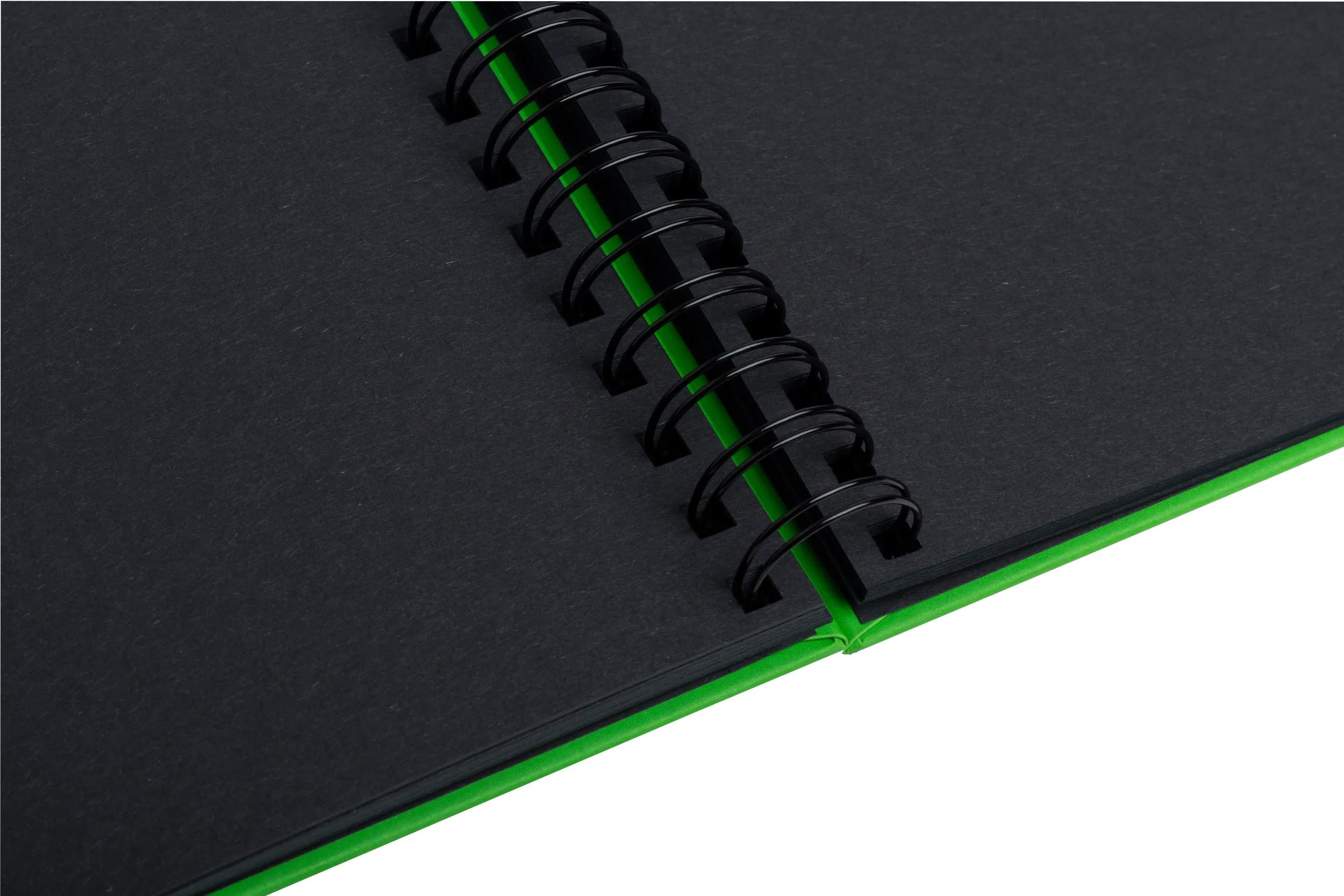 Cuaderno negro con borde verde y espiral negra.