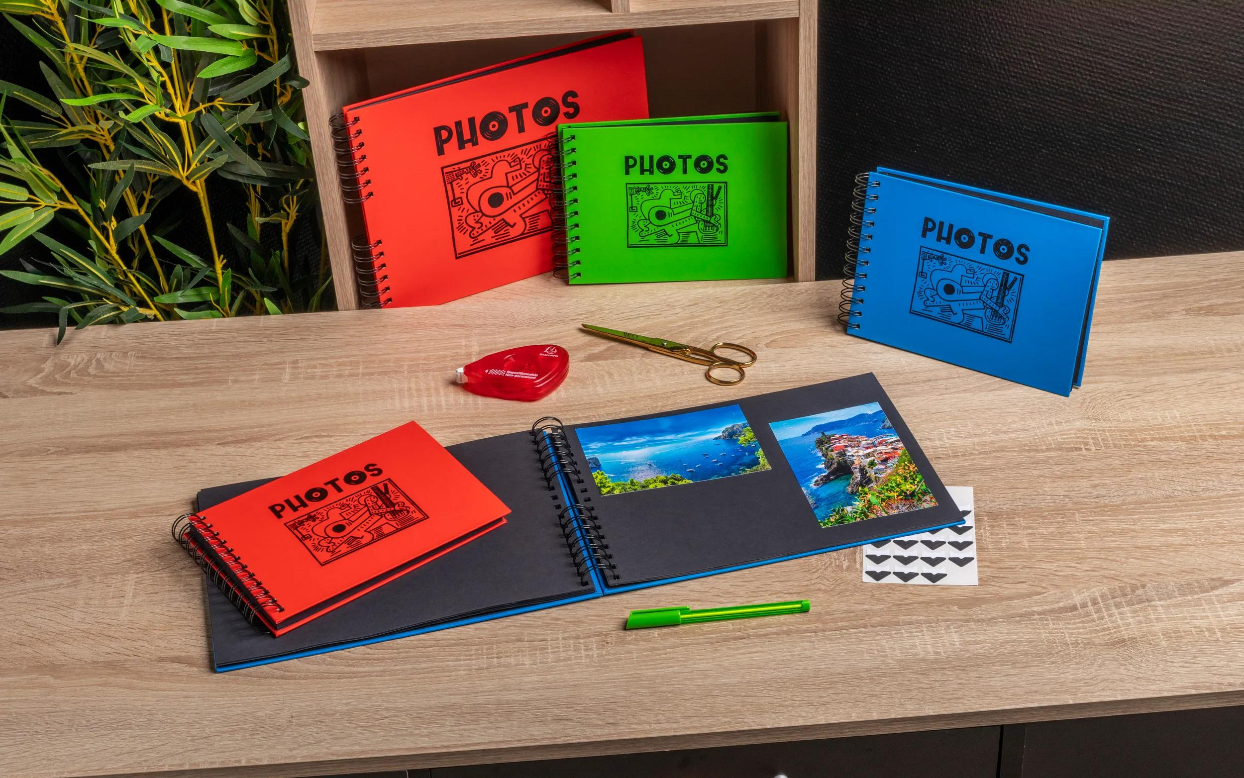 Varios álbumes de fotos en rojo, verde y azul sobre una mesa de madera.