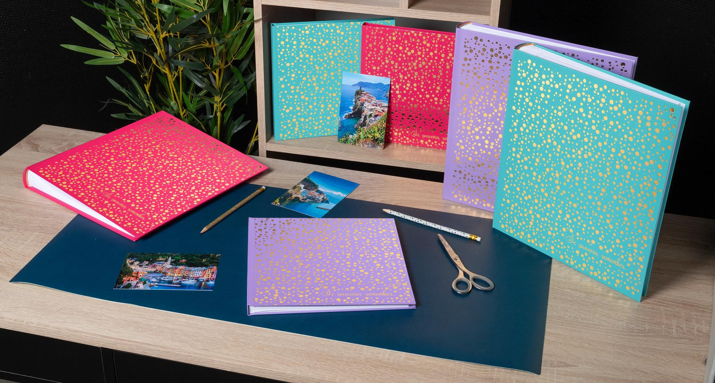 Cuadernos coloridos con puntos dorados sobre un escritorio con fotos.