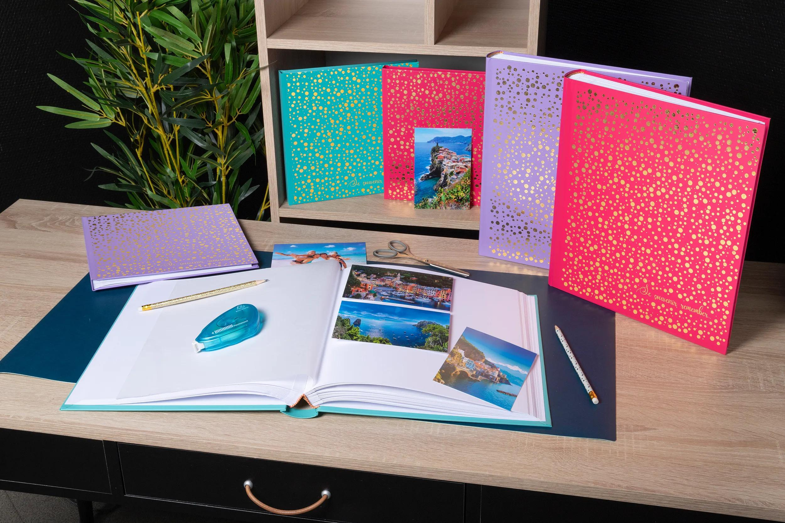 Un álbum de fotos abierto con fotos de viajes, bolígrafos y tijeras sobre un escritorio.
