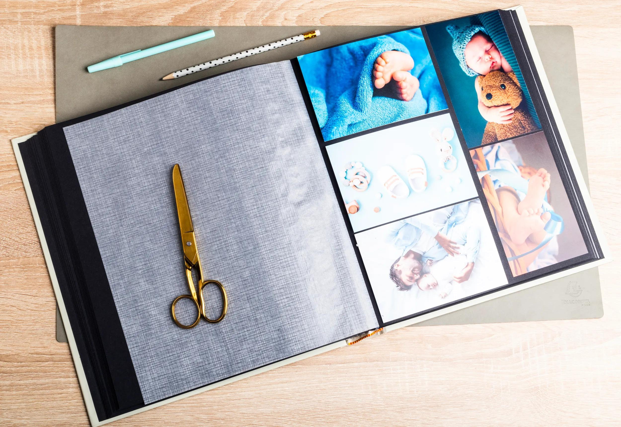 Un álbum de fotos abierto con fotos de bebés y tijeras sobre una mesa de madera.