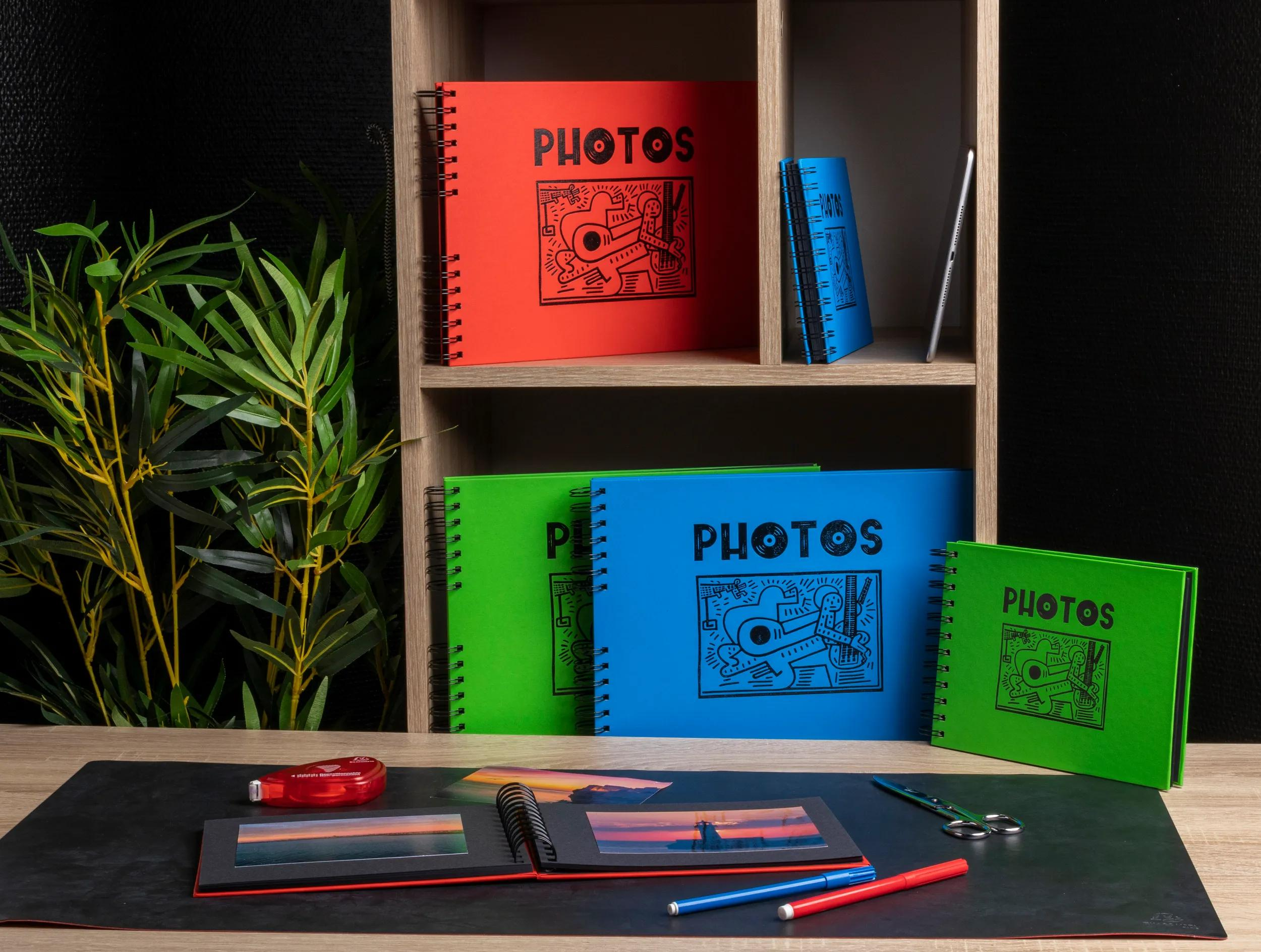 Álbumes de fotos coloridos con arte de Keith Haring sobre un escritorio con plantas.