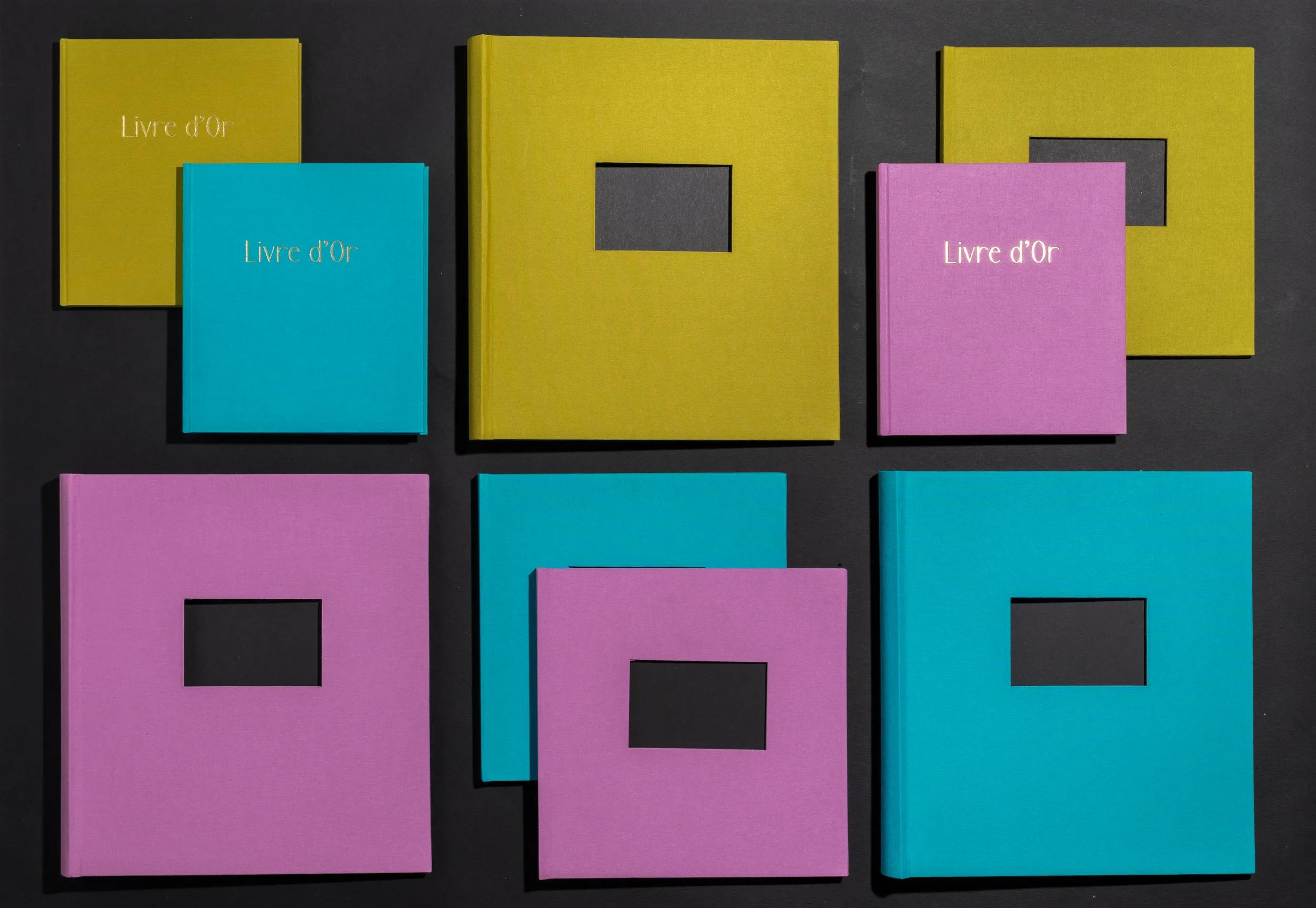 Varios libros coloridos con texto „Livre d'Or“ sobre fondo negro.