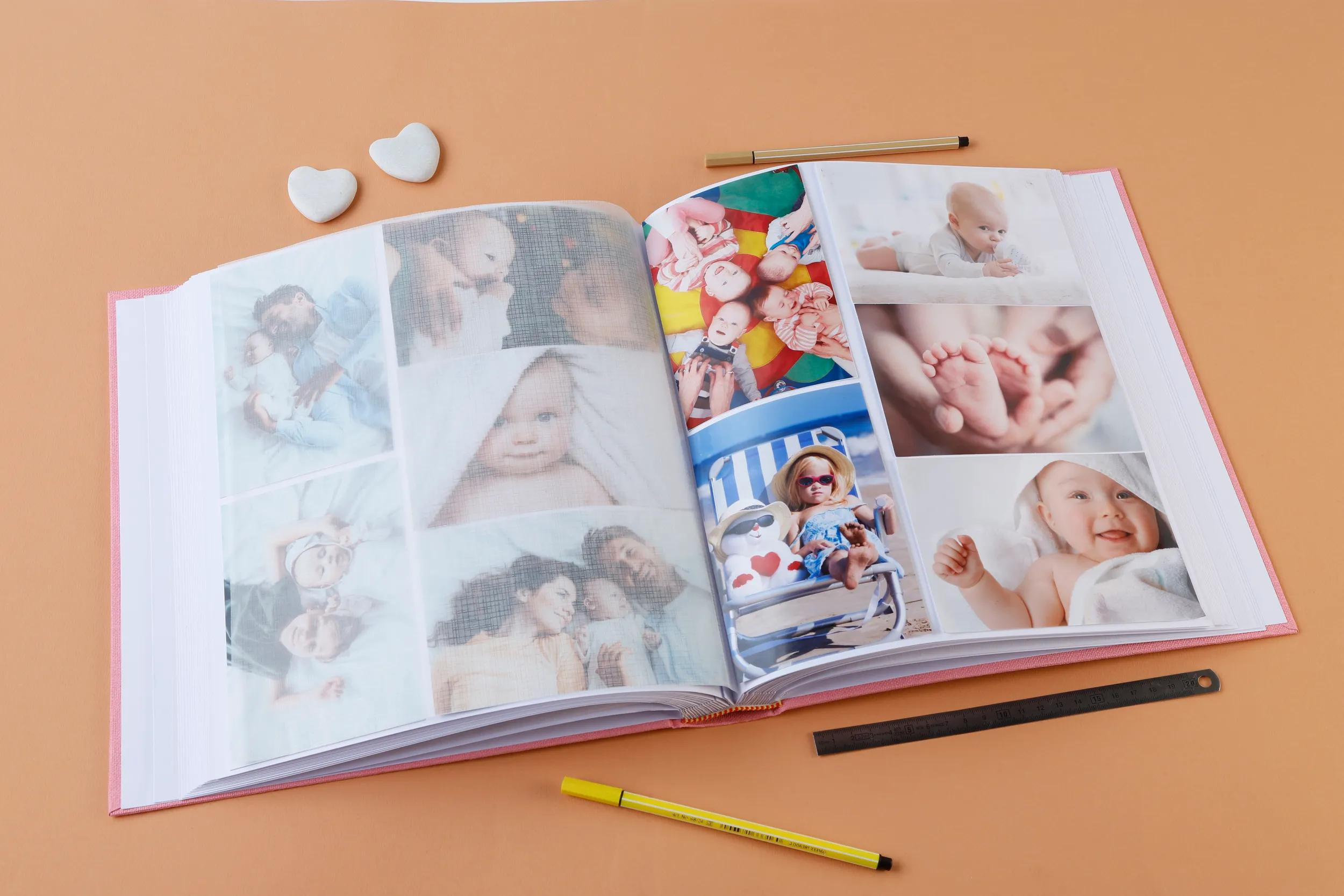 Un álbum de fotos abierto con fotos de bebés, bolígrafos y piedras en forma de corazón.