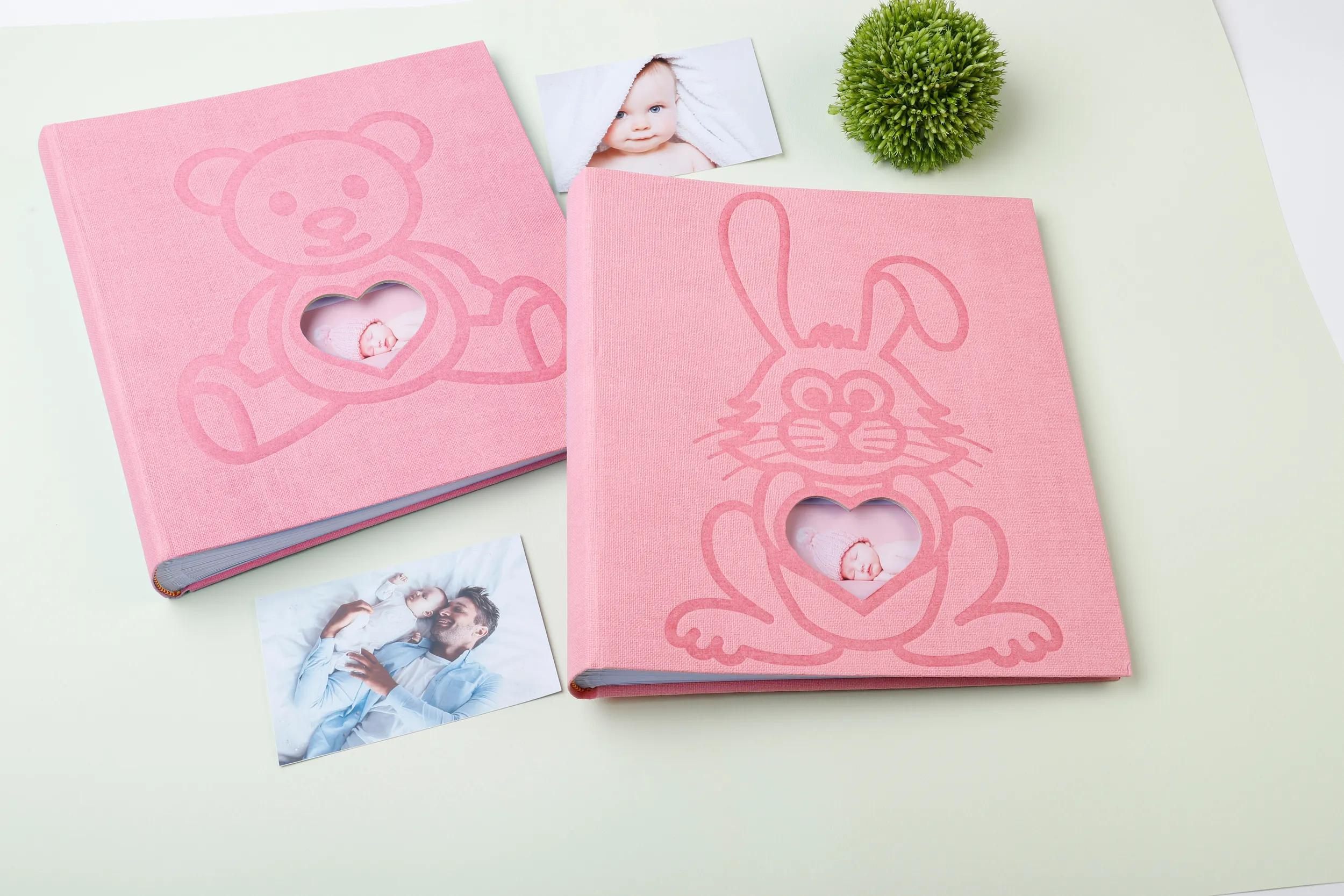 Dos álbumes de fotos rosas con diseños de osito y conejito, junto a fotos de bebés y una planta.