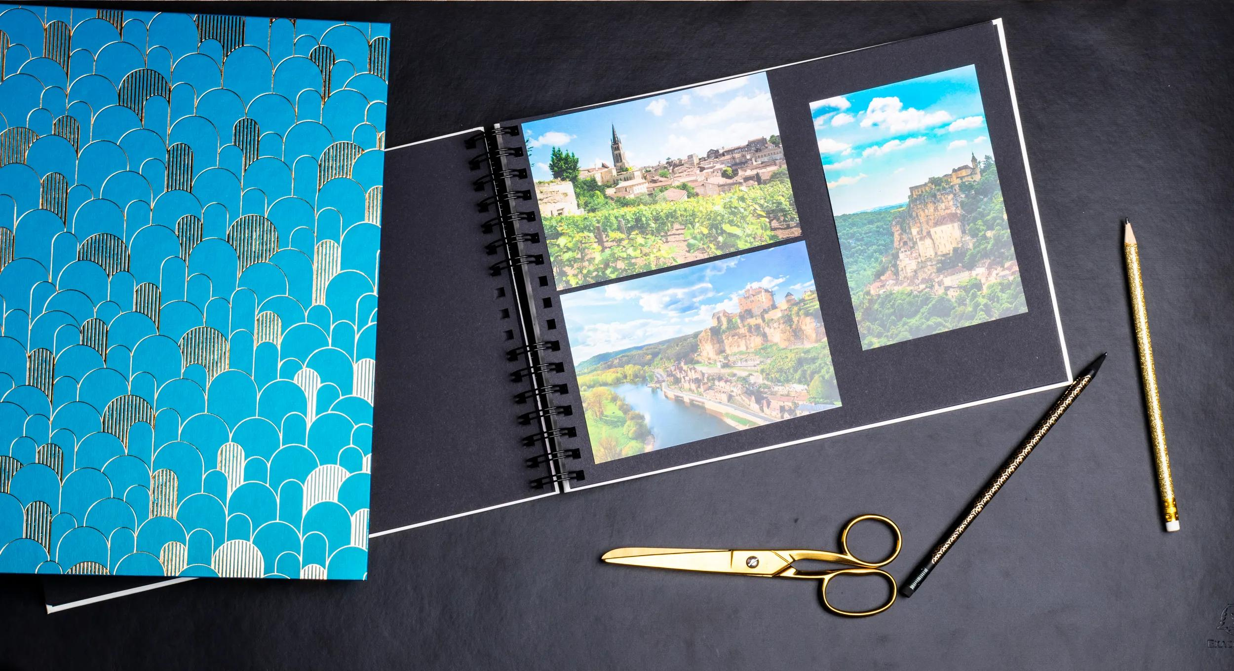 Un álbum de recortes abierto con fotos de ciudades y paisajes, tijeras y lápices cerca.