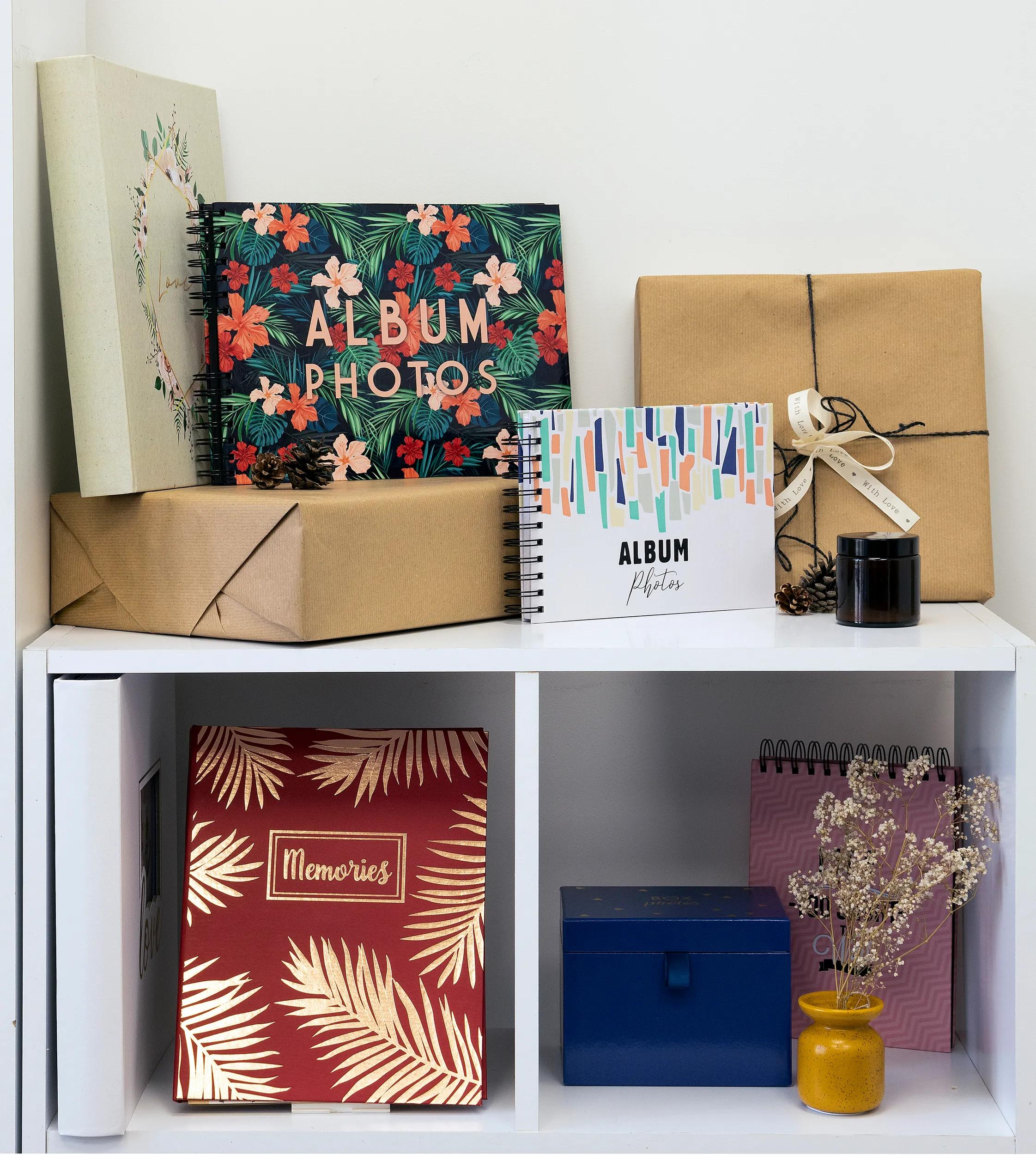 Varios álbumes de fotos y regalos en estantes blancos.