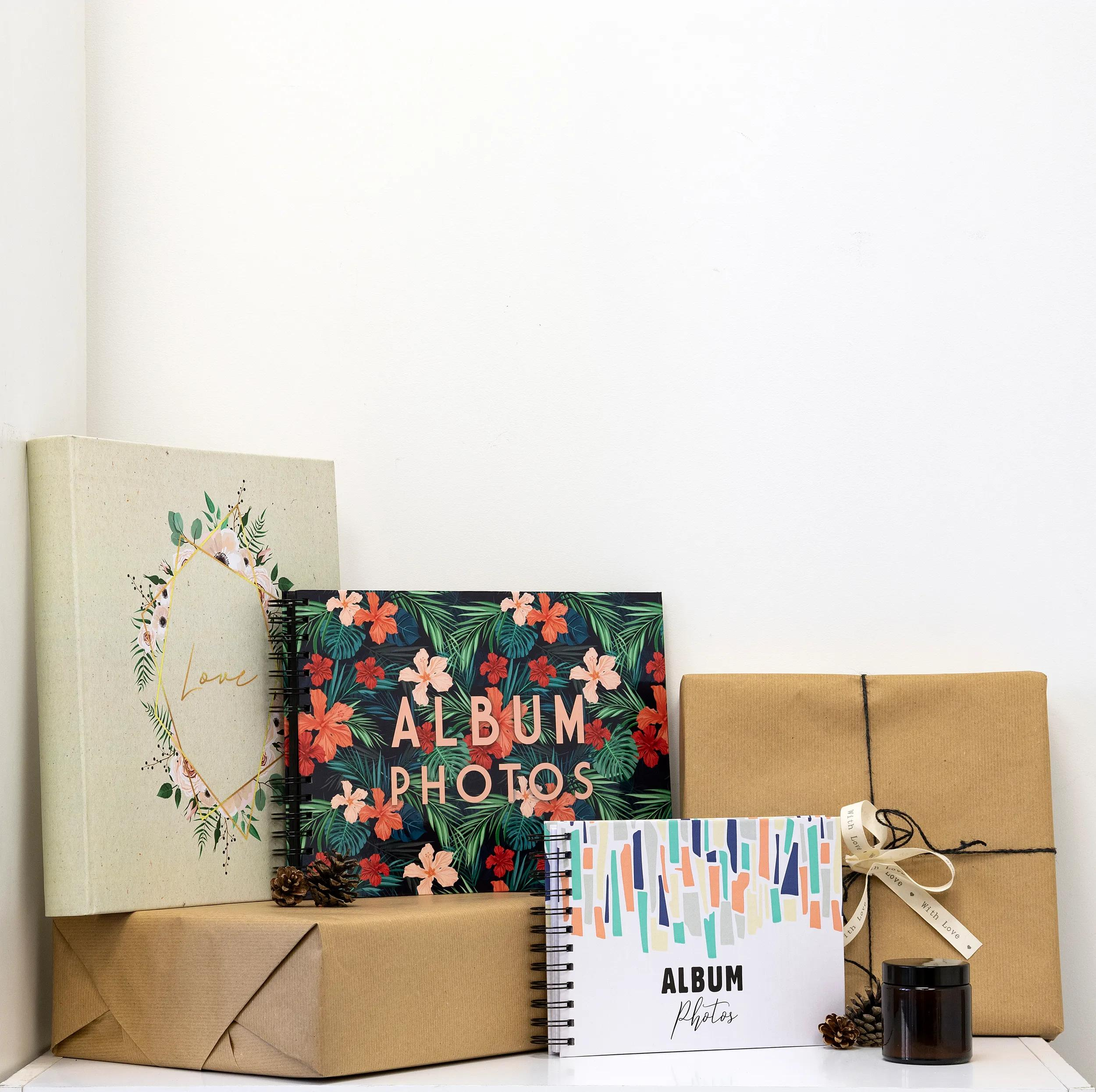 Varios álbumes de fotos y regalos con piñas y un frasco sobre fondo blanco.