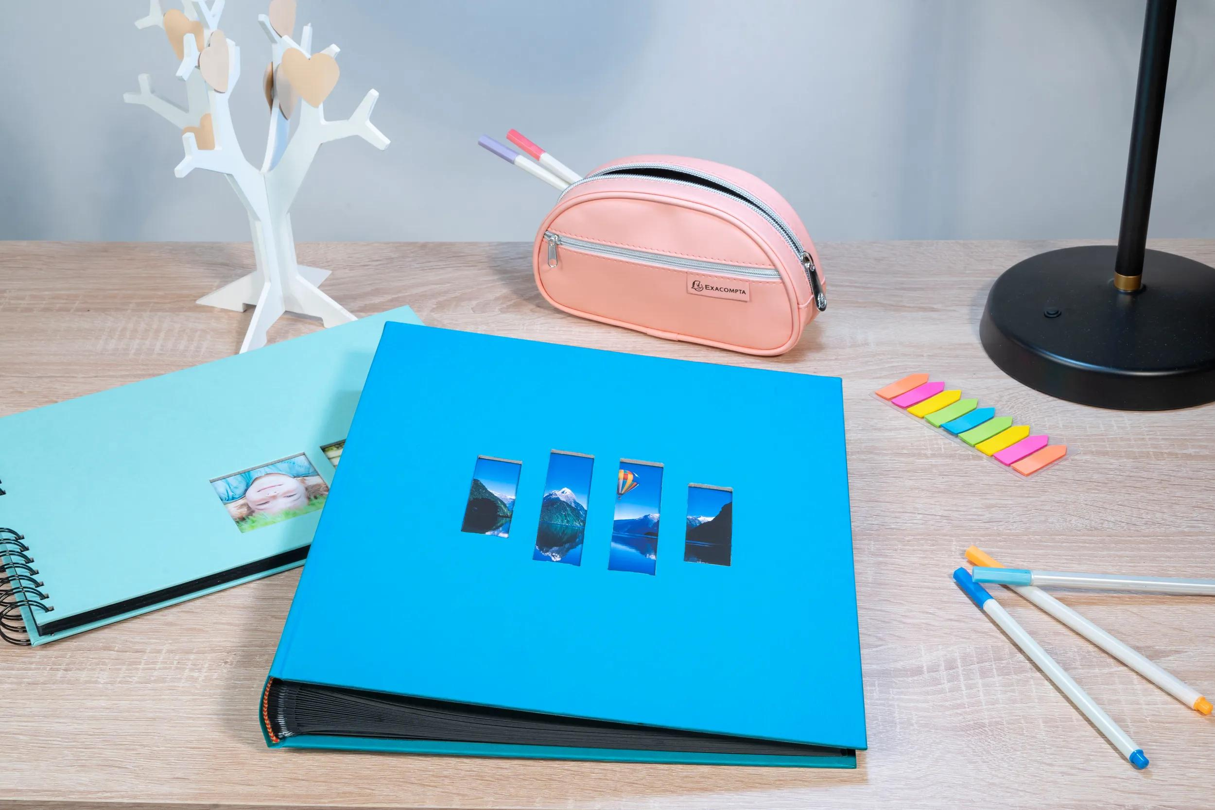 Álbum de fotos azul y azul claro sobre un escritorio de madera con decoración.
