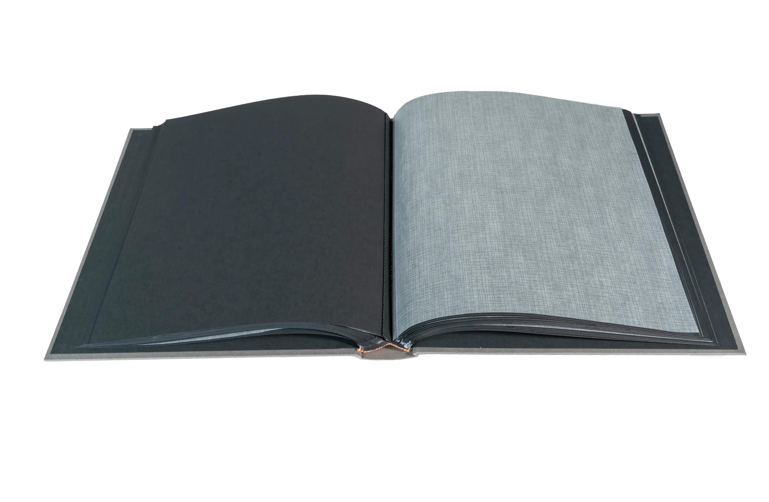Un libro abierto con páginas negras y gris claro, sobre fondo blanco.