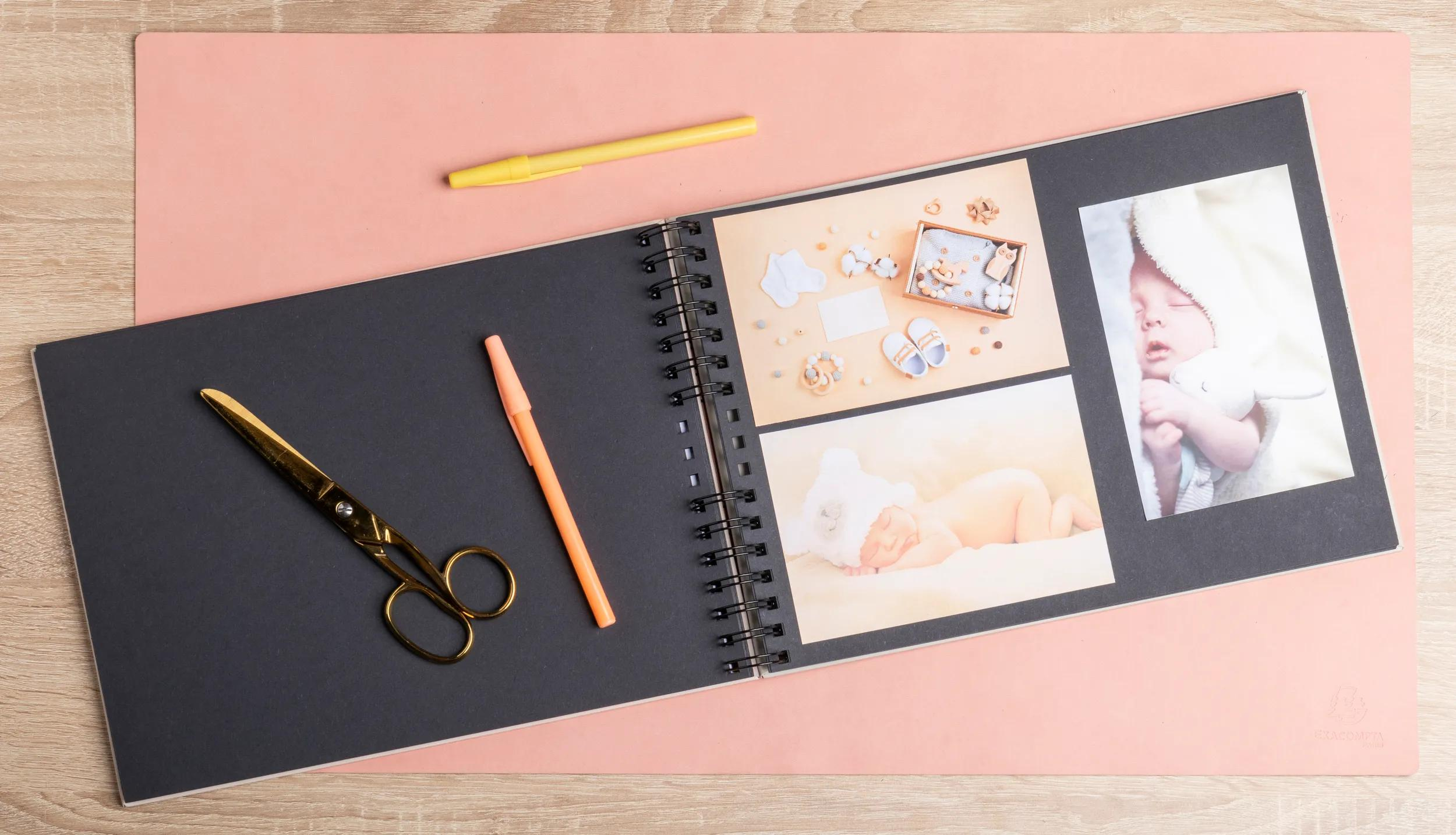 Un álbum de recortes abierto con fotos de bebés, tijeras, bolígrafos y artículos para bebé.