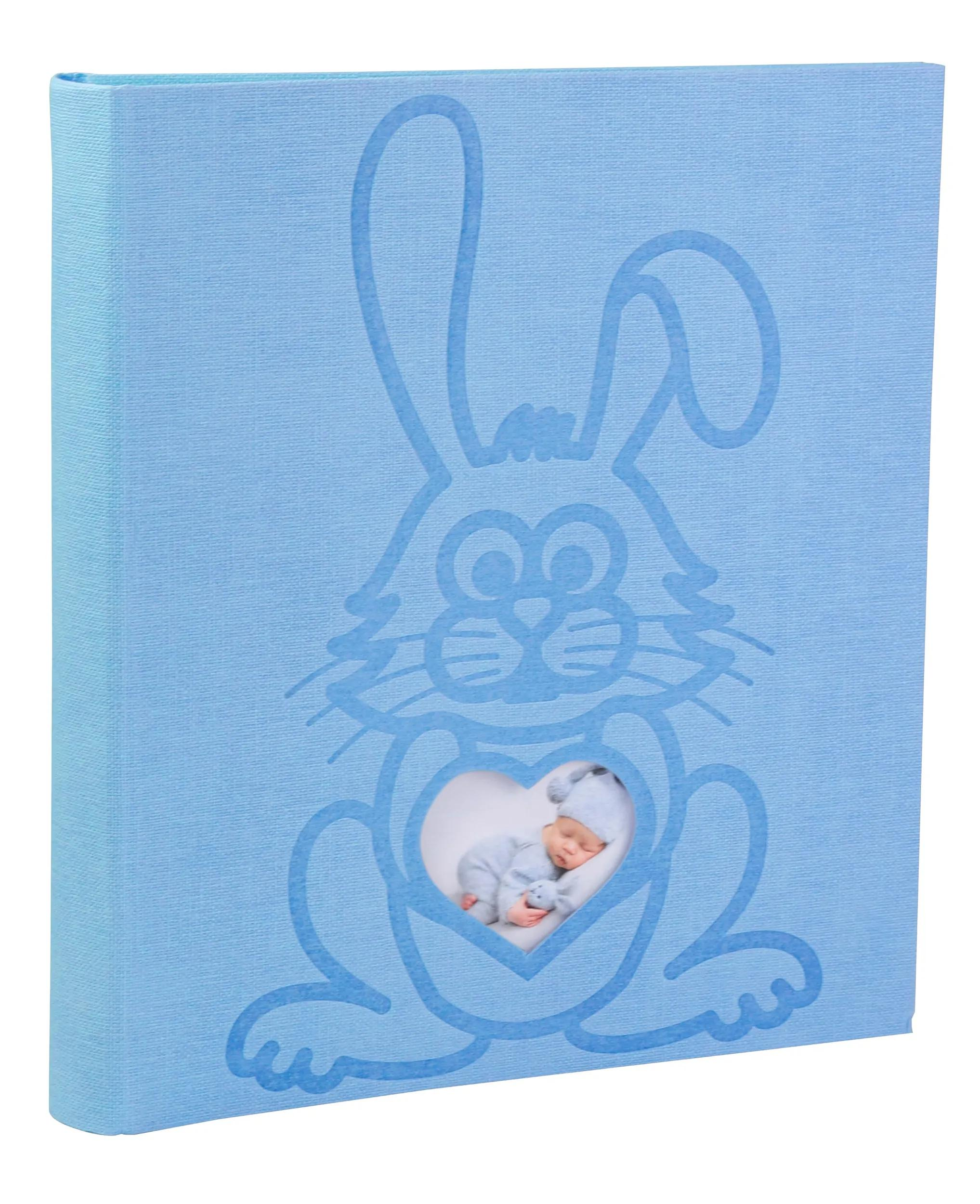 Un álbum azul claro con diseño de conejo. Un bebé duerme en la ventana del corazón.