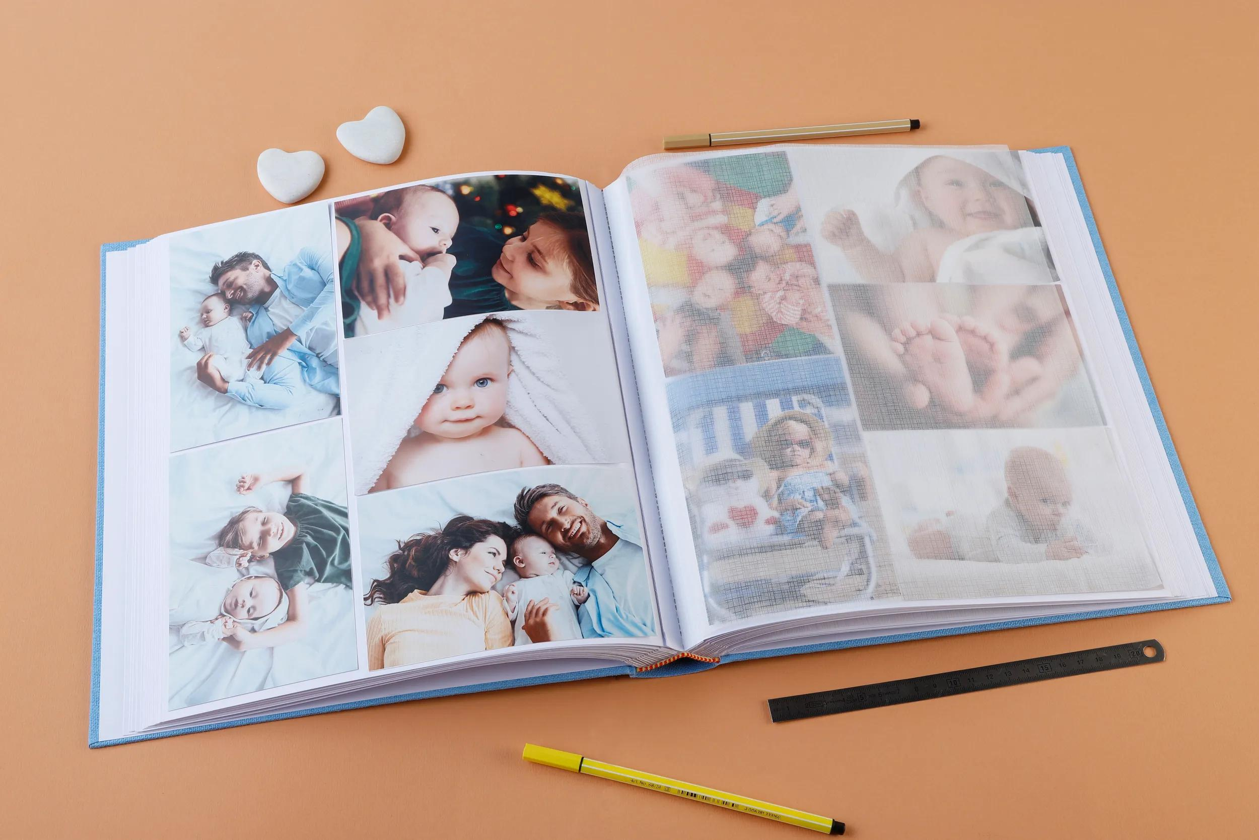 Un álbum de fotos abierto con fotos de bebés, corazones y bolígrafos sobre fondo naranja.