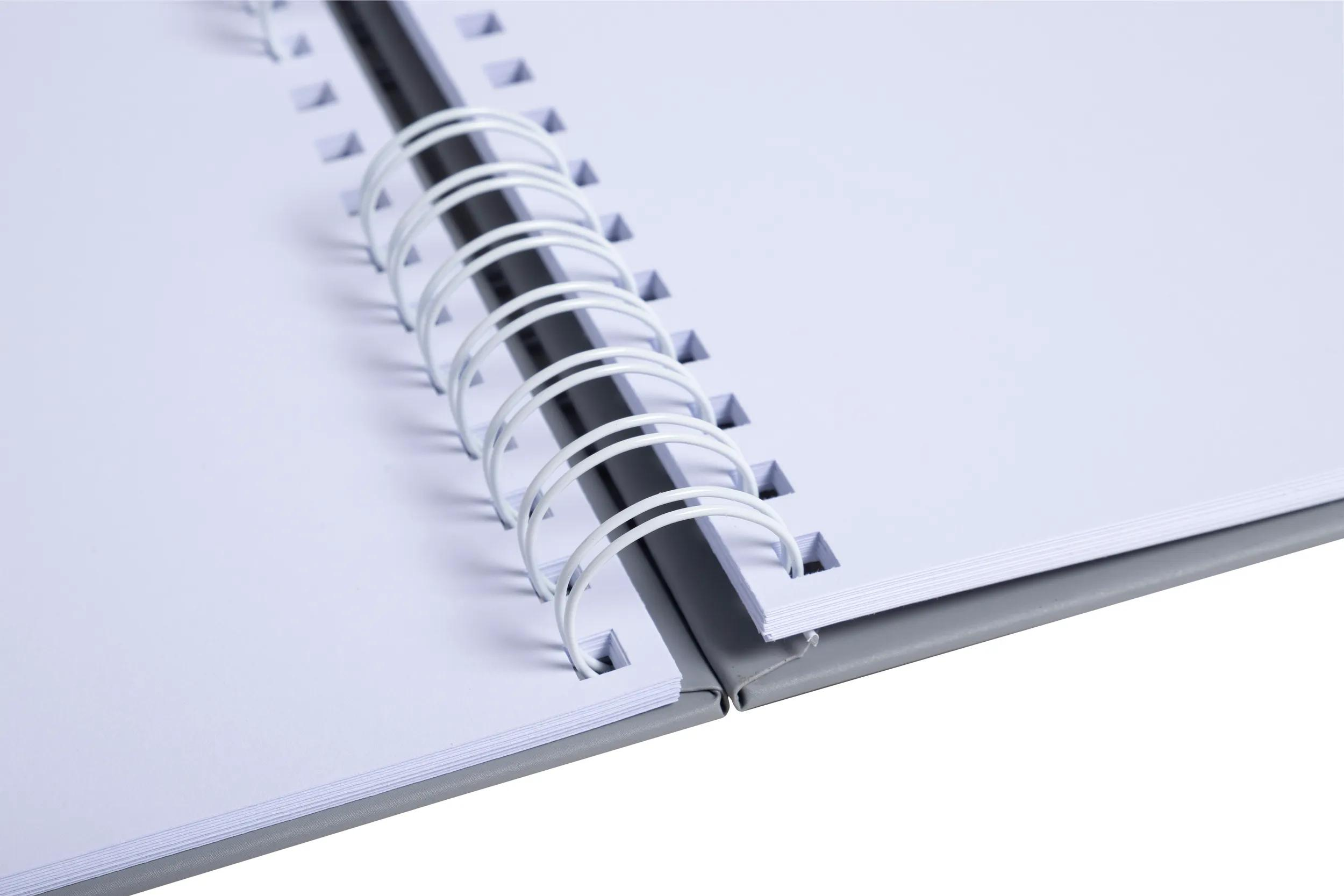 Un cuaderno abierto con páginas blancas y encuadernación de espiral plateada.