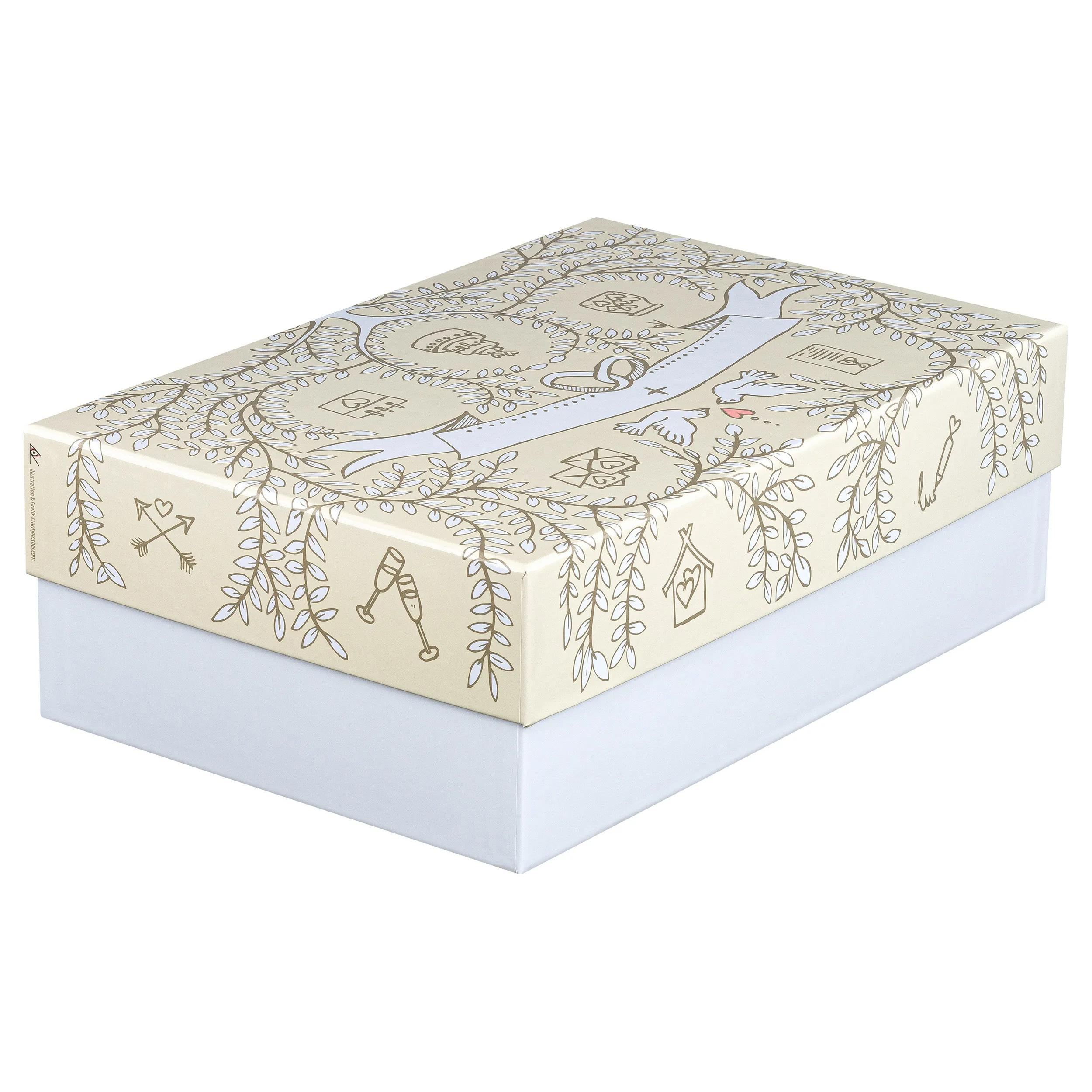 Una caja color crema decorada con ramas, corazones, pájaros y motivos de casas.
