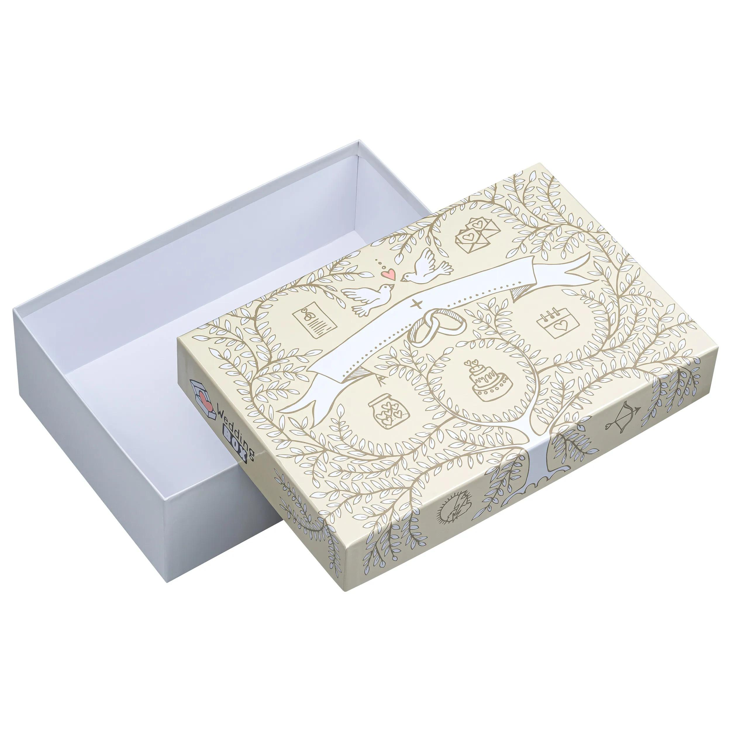 Una caja de regalo abierta, color crema, decorada con motivos de boda, flores y palomas.