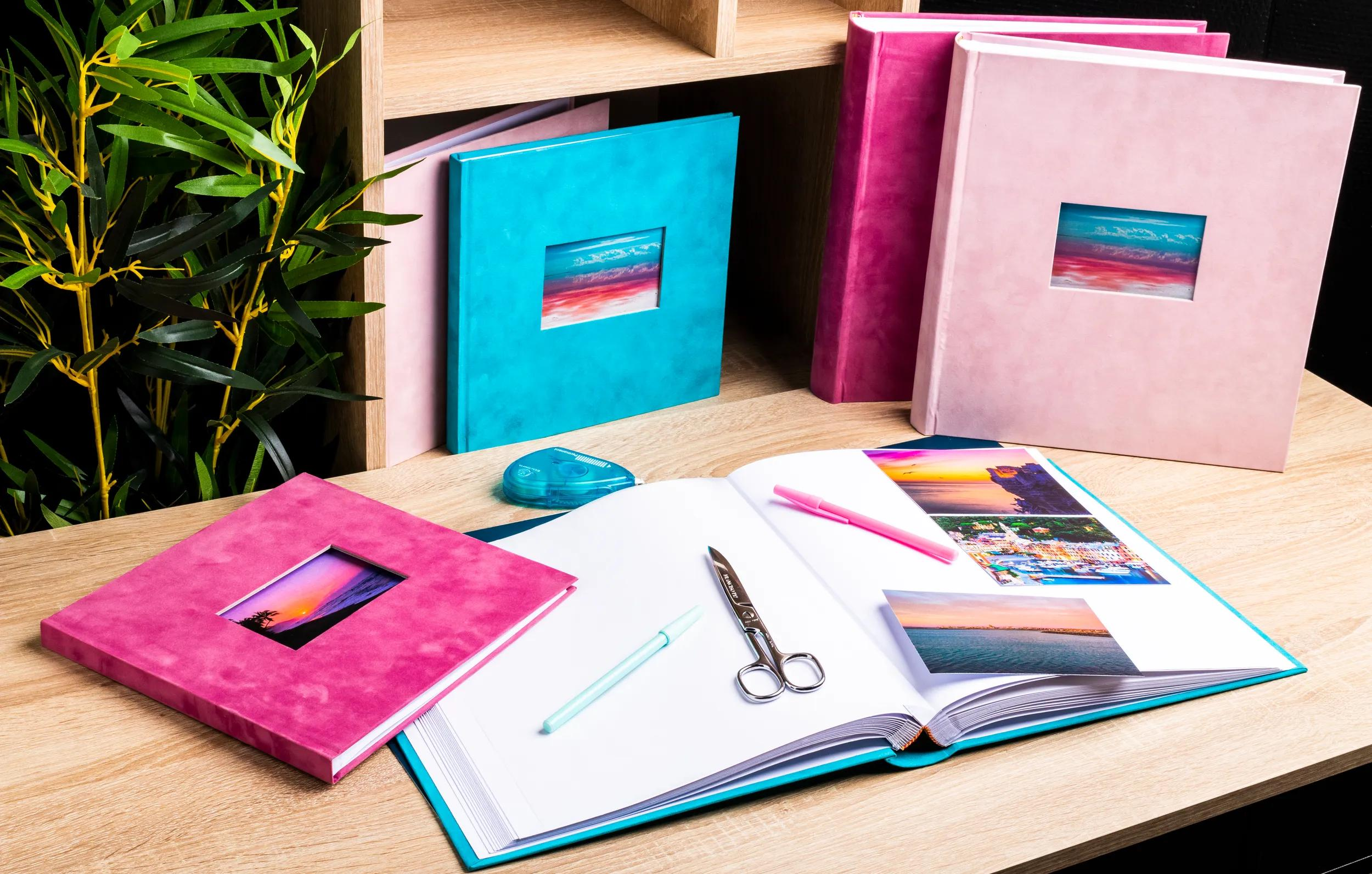 Álbumes de fotos en rosa, azul y rosa en una mesa de madera.
