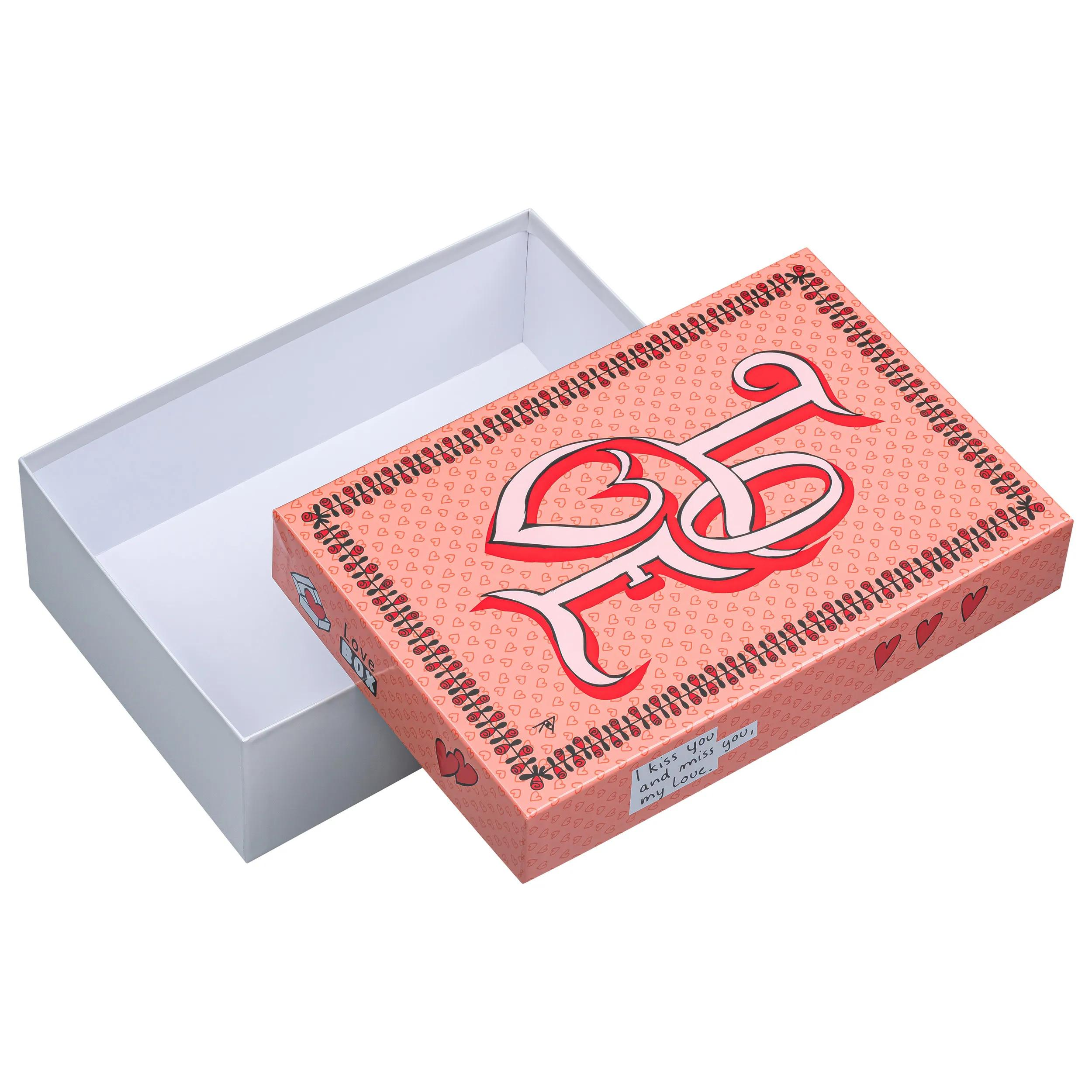 Una caja de regalo rosa con estampado de corazones, letras y rosas. Interior blanco.