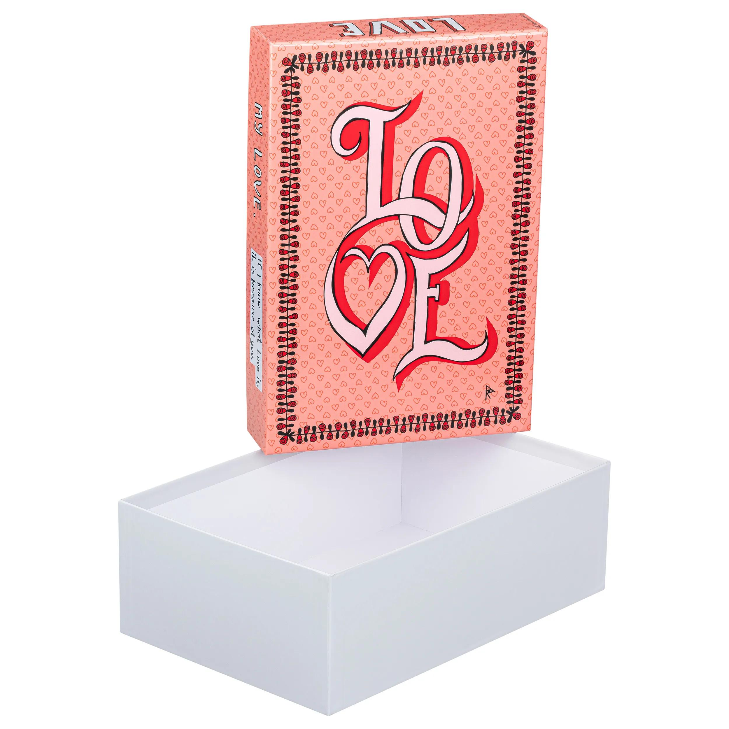 Una caja rosa con corazones y texto LOVE, sobre una caja blanca abierta.