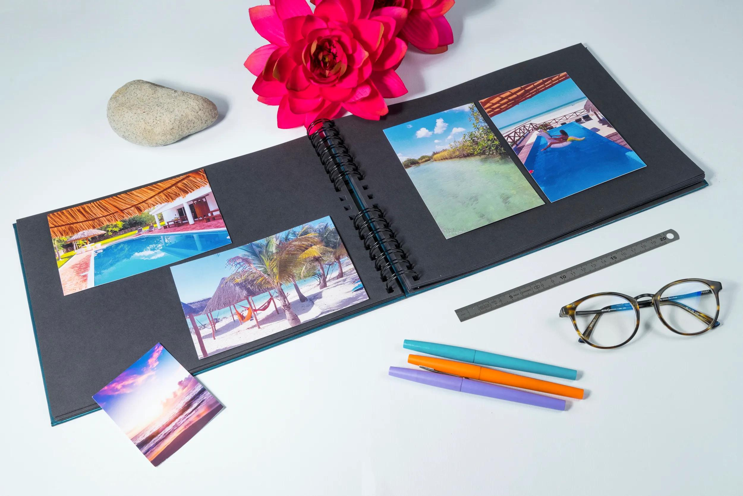 Álbum de fotos abierto con fotos de viajes, flores, piedra y útiles de escritura.