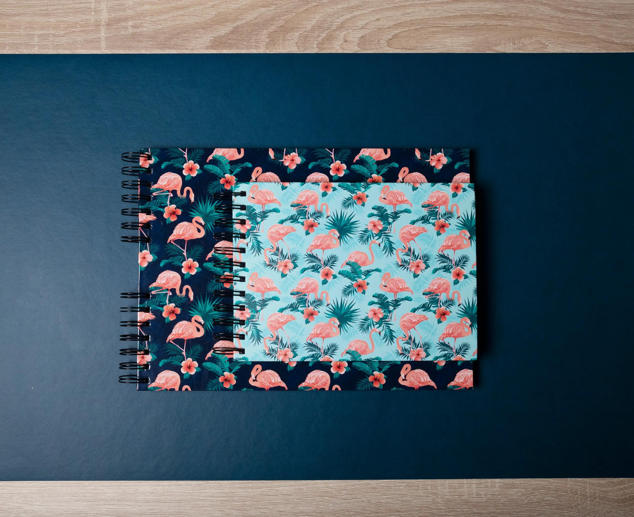 Dos cuadernos con estampado de flamencos sobre fondo azul oscuro.