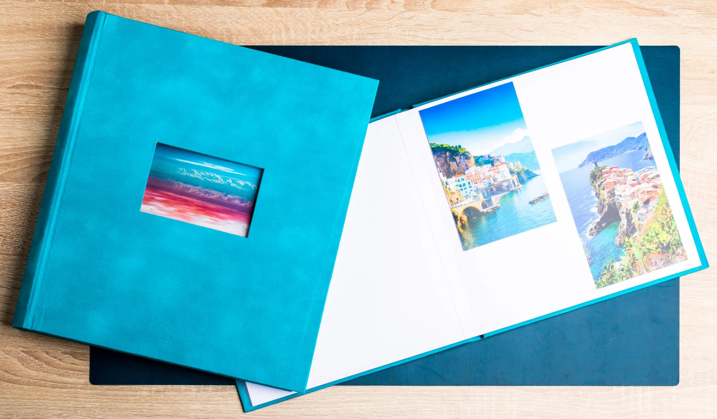 Un álbum de fotos turquesa abierto con fotos de viajes sobre una alfombrilla azul.