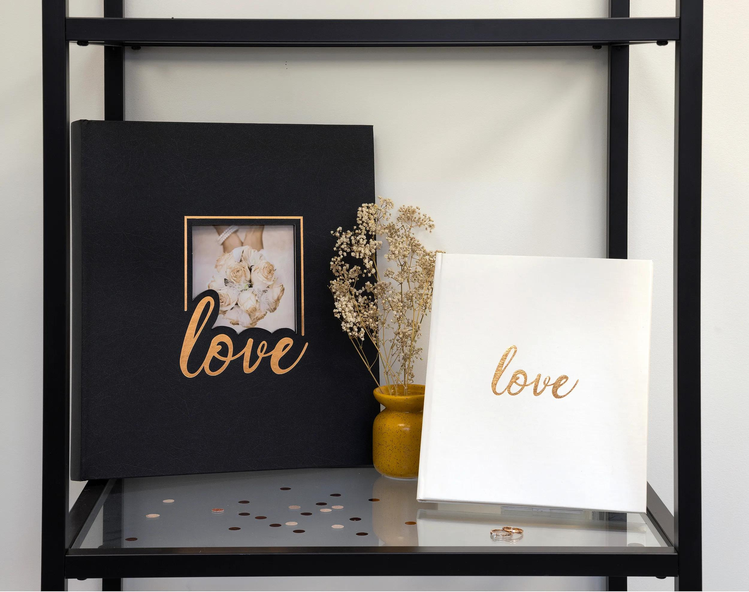 Un libro negro y uno blanco con letras "love" en un estante.