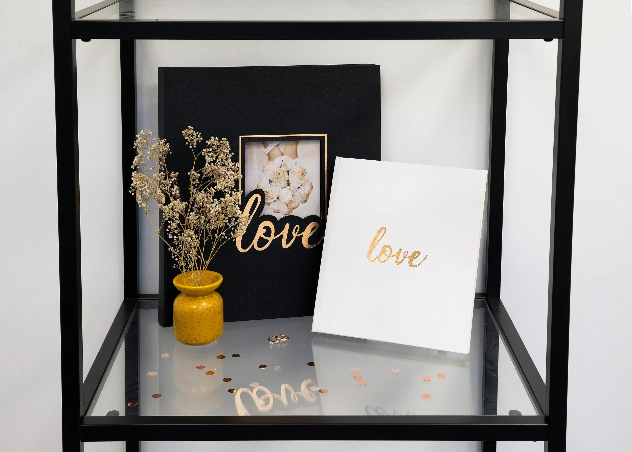 Dos álbumes de fotos, un jarrón amarillo con flores secas, anillos y confeti.