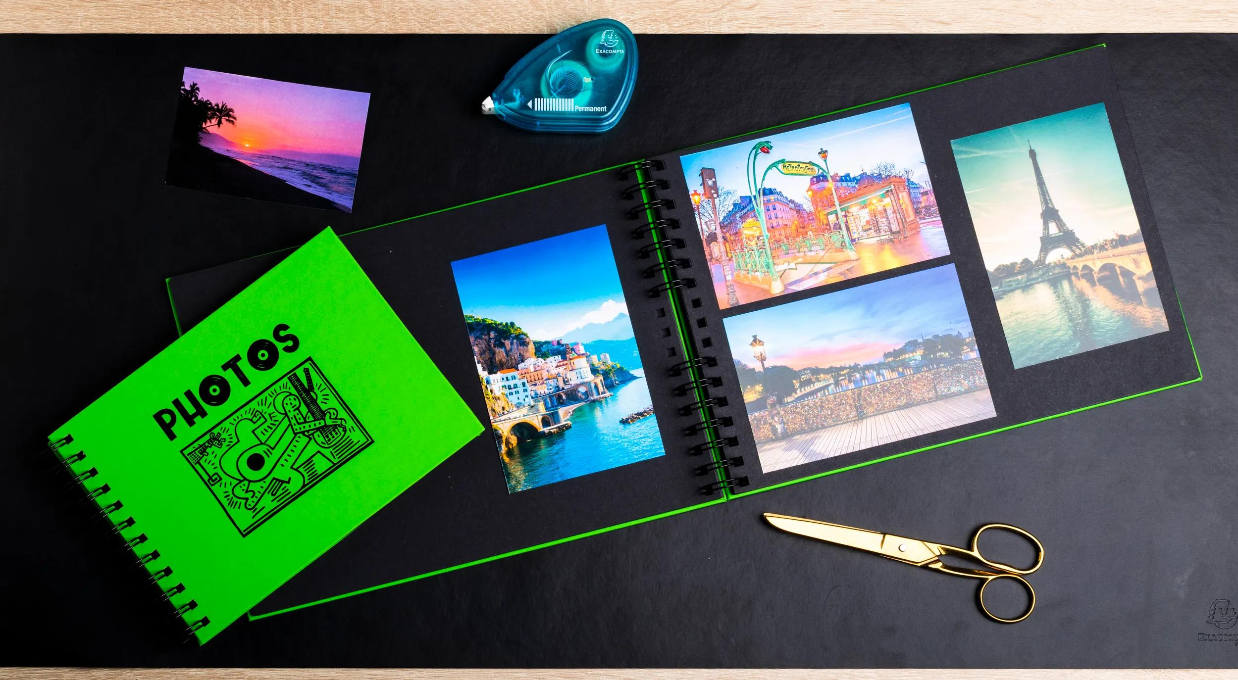 Un álbum de fotos abierto con fotos de viajes, tijeras y cinta sobre fondo negro.