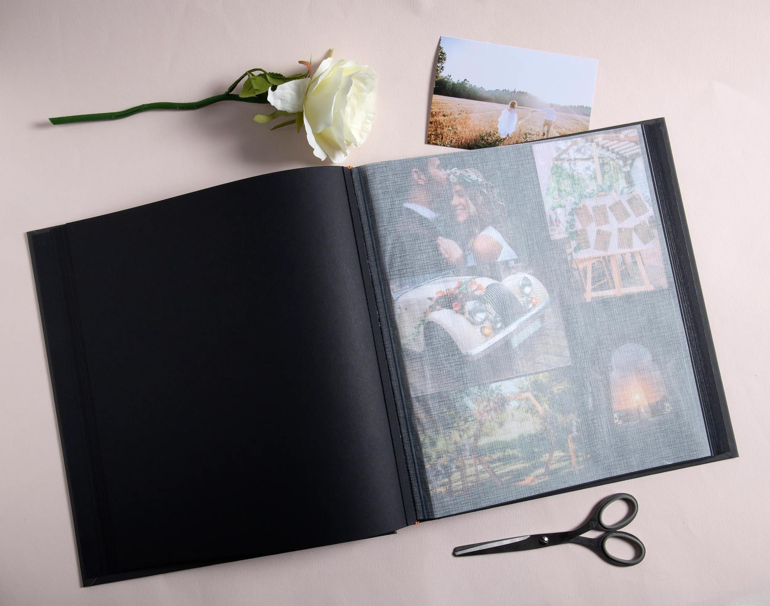 Un álbum de fotos abierto con fotos, una rosa y tijeras sobre un fondo claro.