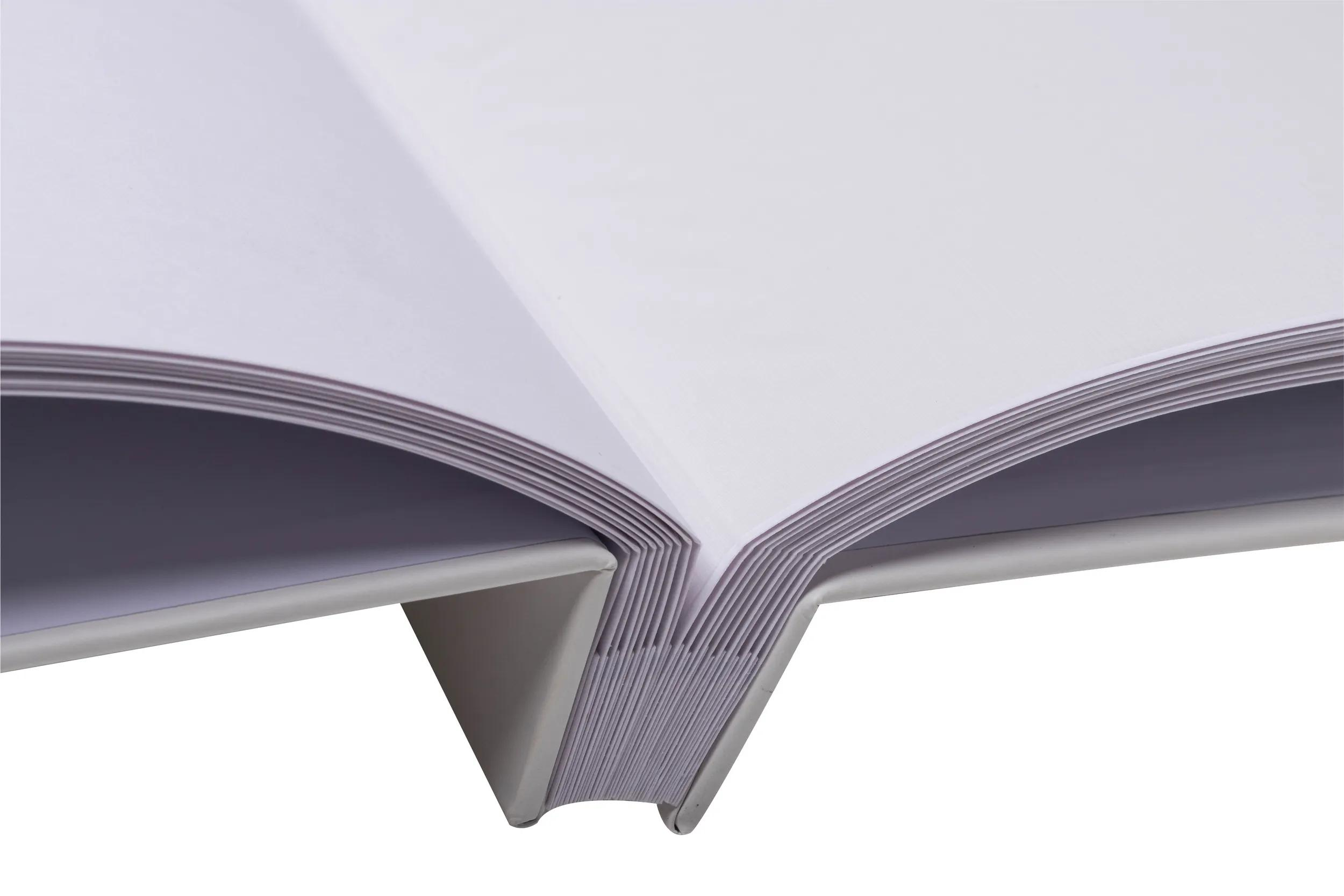 Primo piano di un libro aperto con pagine bianche e rilegatura grigia.
