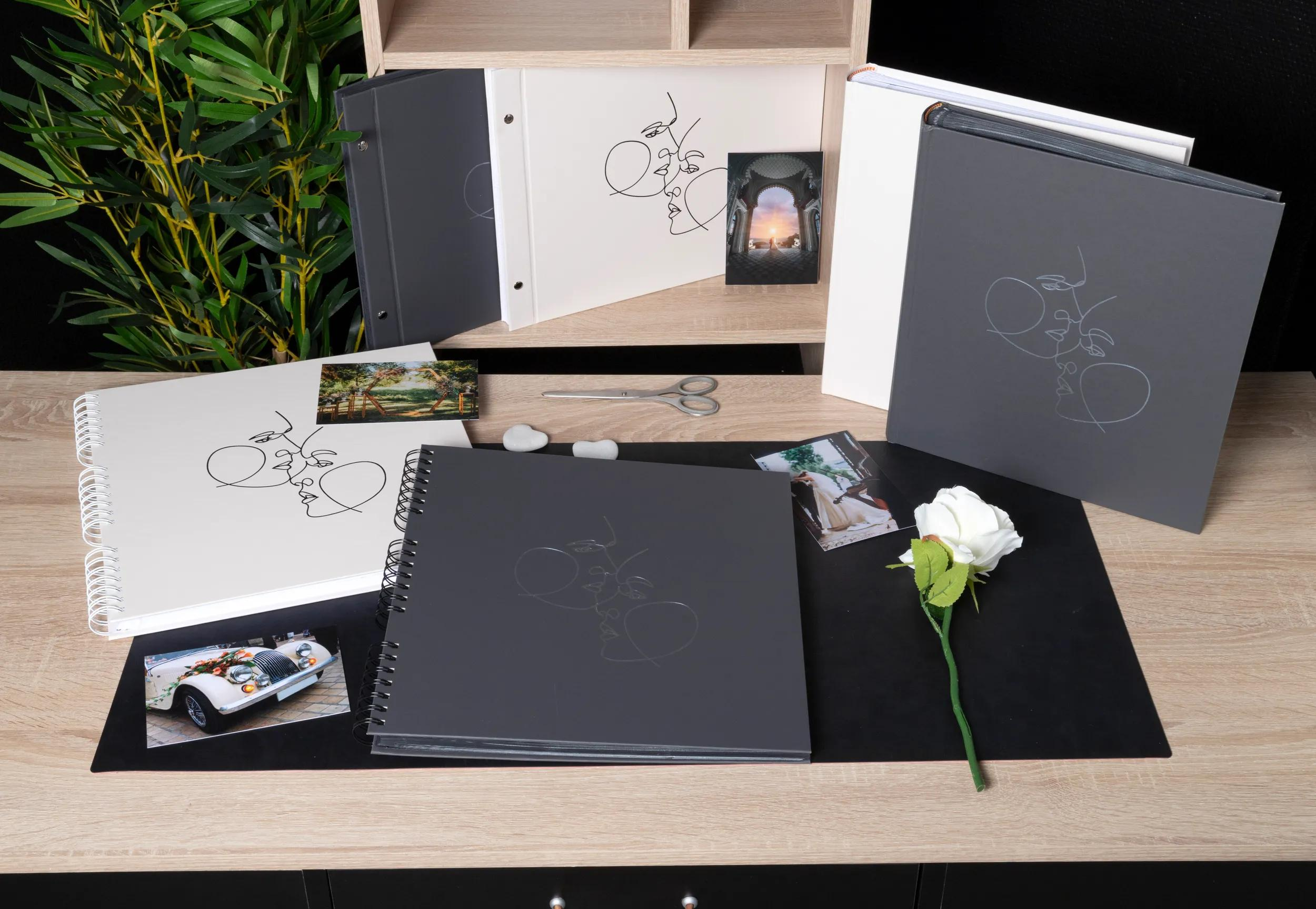 Varios álbumes de fotos, una rosa blanca y una lupa sobre una mesa de madera.
