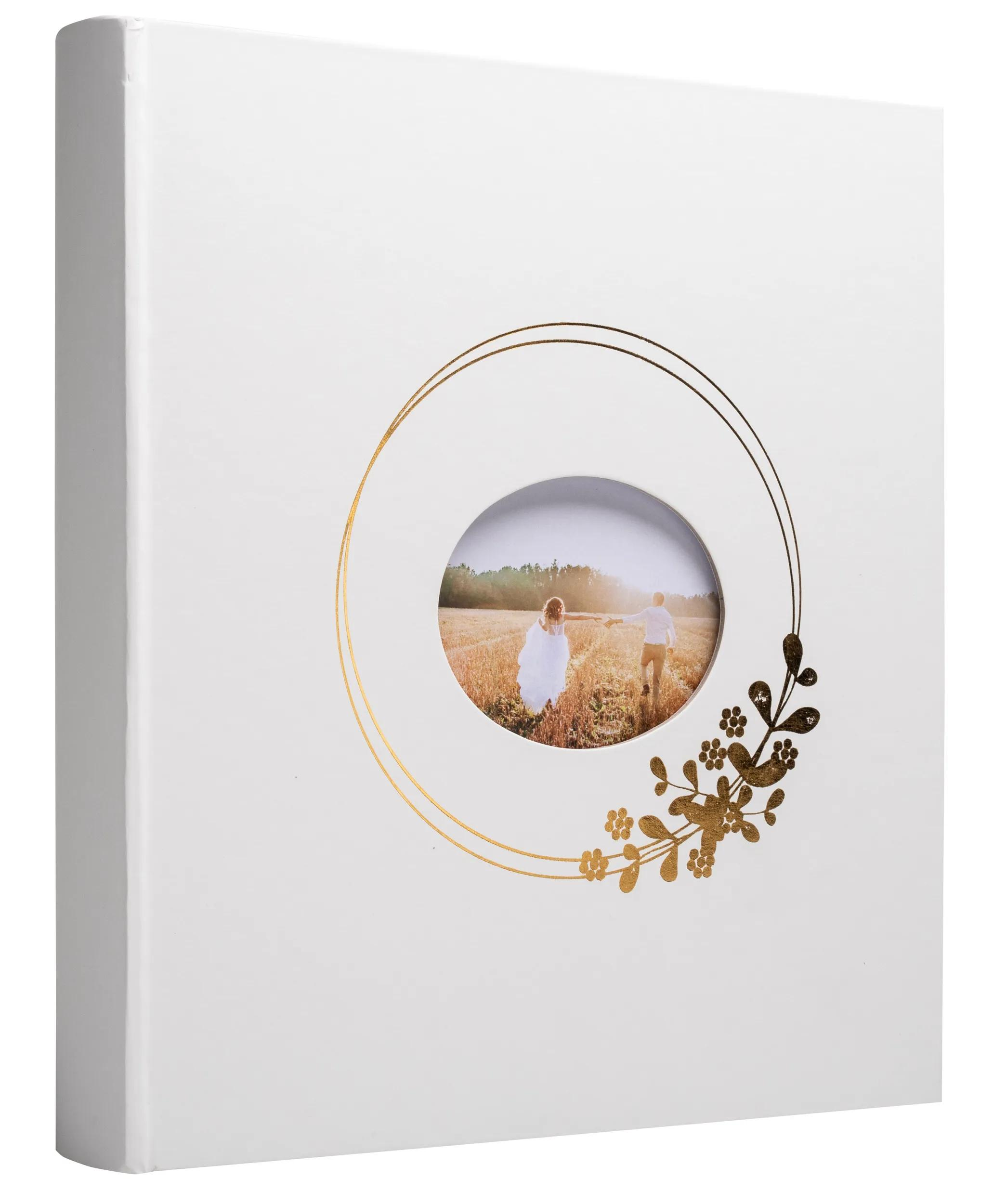 Un álbum blanco con decoración dorada y una foto ovalada de una pareja.