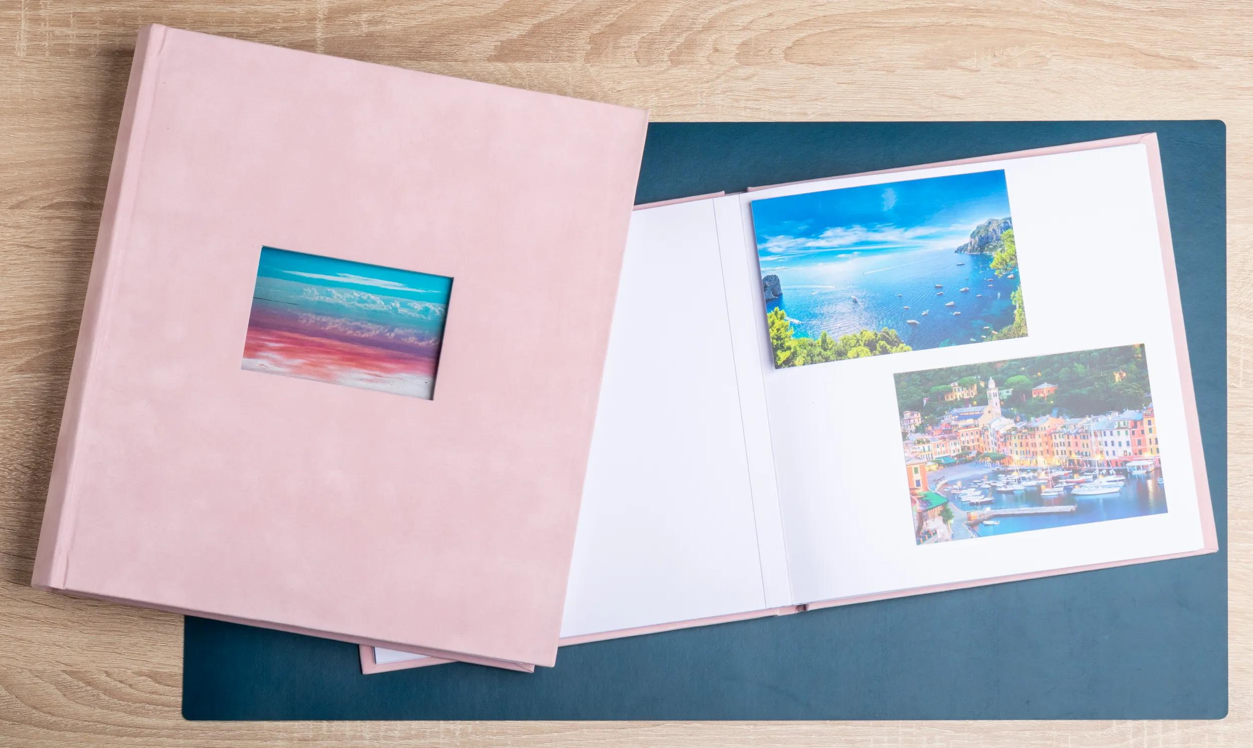 Un álbum de fotos rosa está abierto sobre una mesa de madera, mostrando dos imágenes de paisajes.