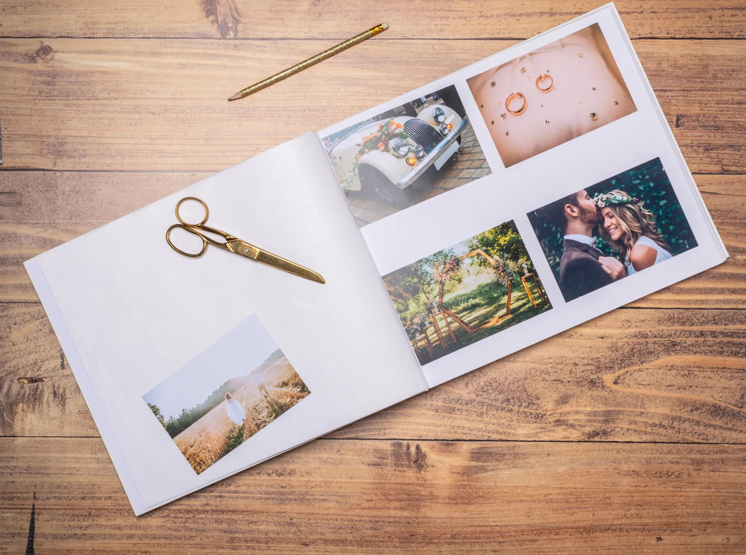 Un álbum de bodas abierto con fotos, tijeras y lápiz sobre fondo de madera.