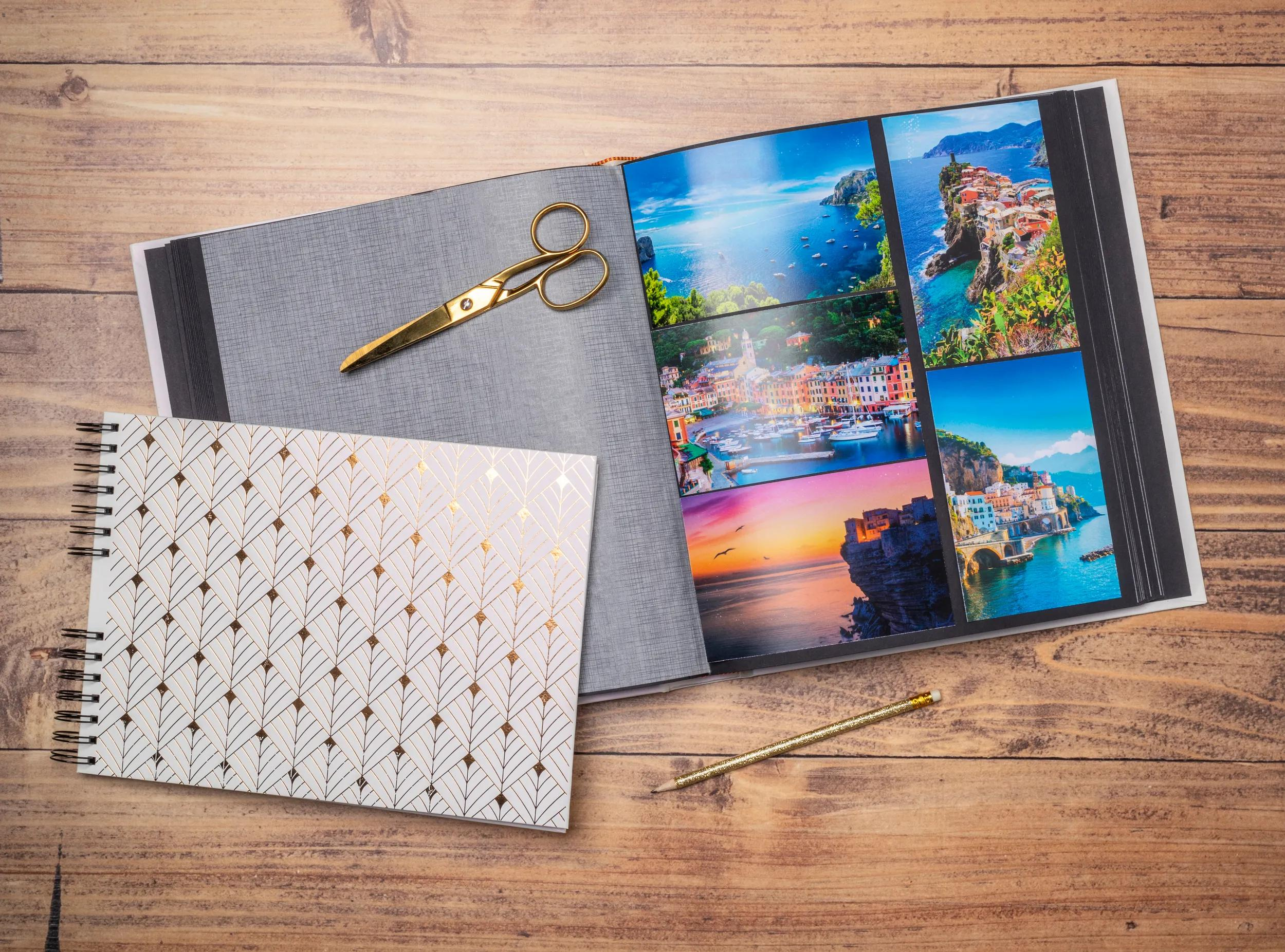Un álbum de fotos abierto con fotos de vacaciones, tijeras y lápiz sobre mesa de madera.