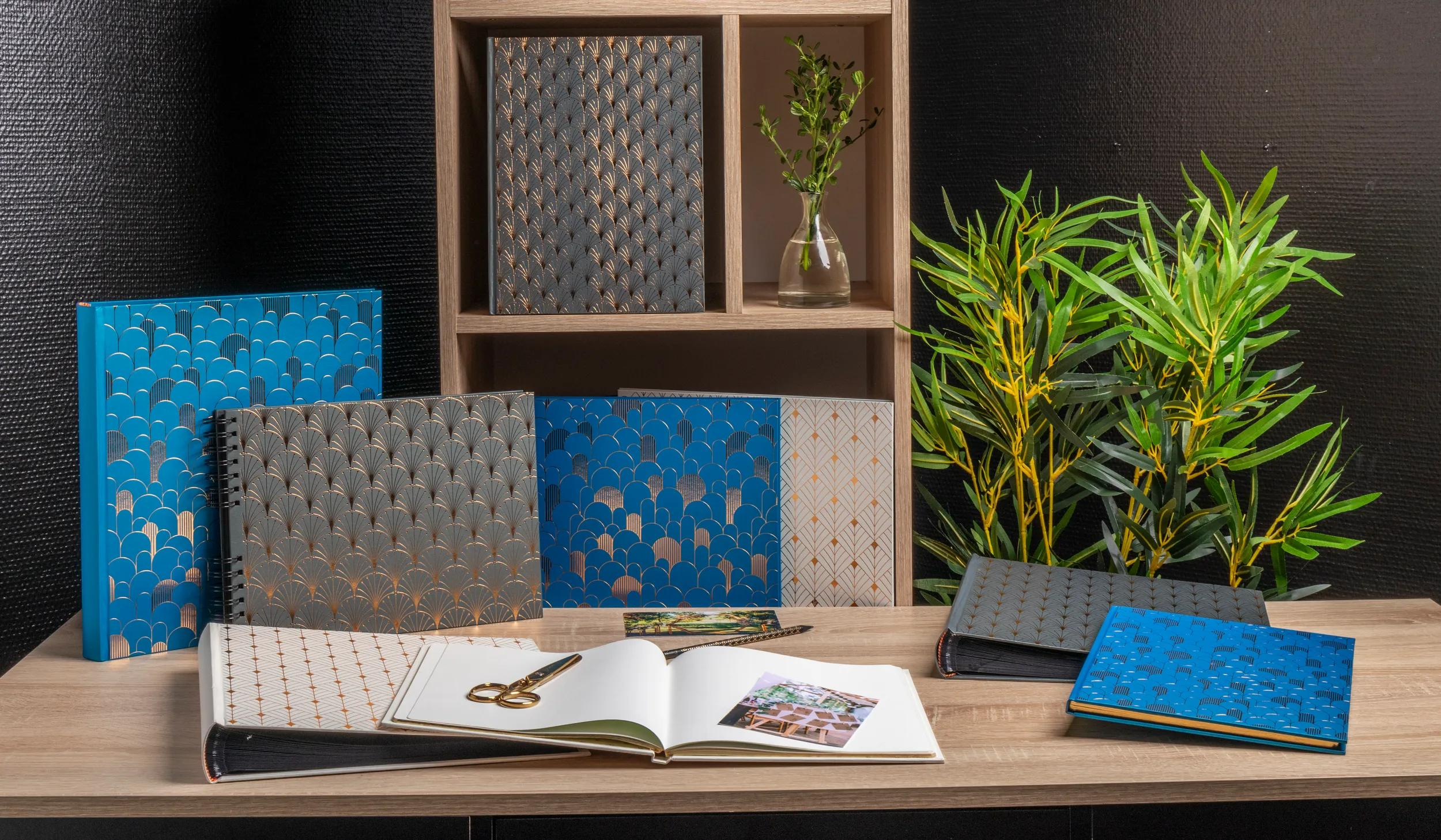 Una colección de álbumes de fotos y cuadernos con patrones decorativos sobre una mesa de madera.