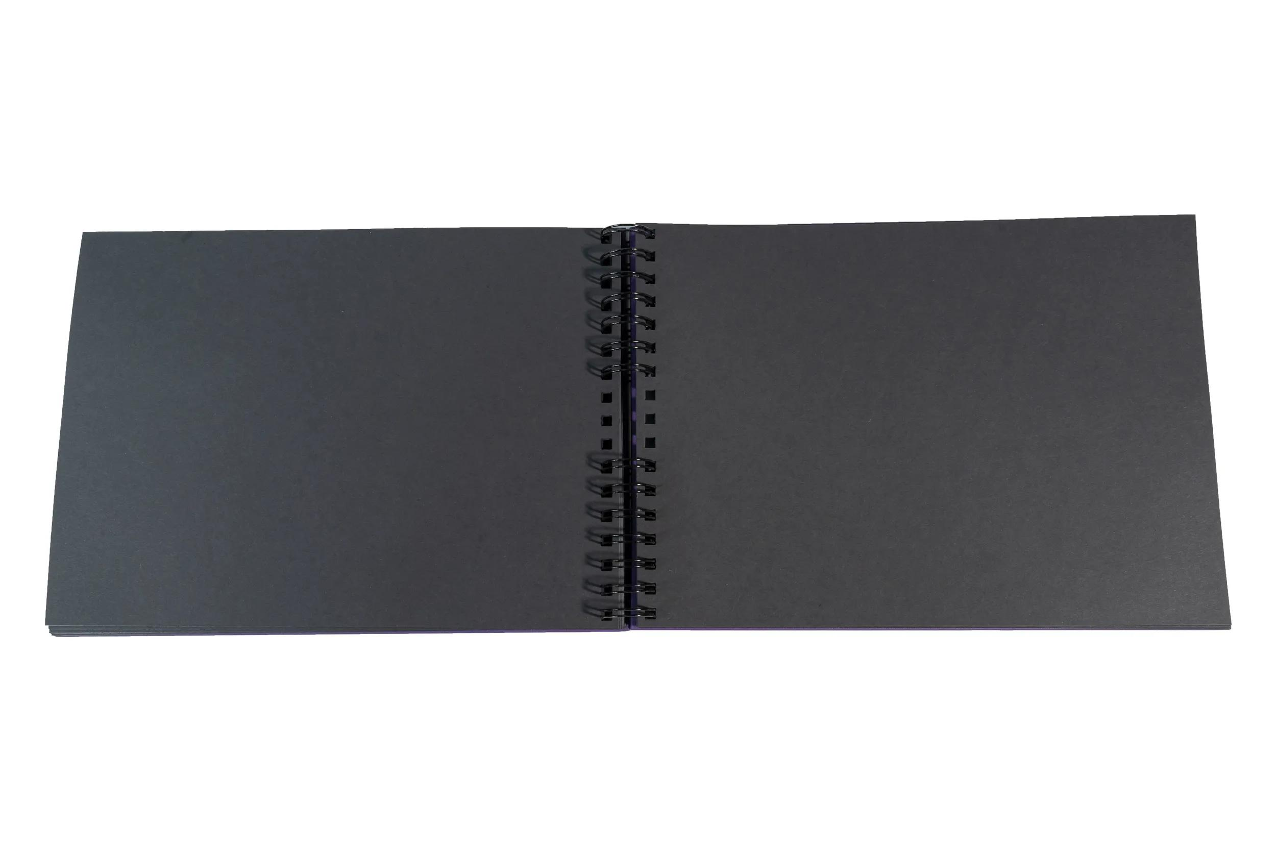 Un cuaderno abierto de espiral negro sobre fondo blanco.