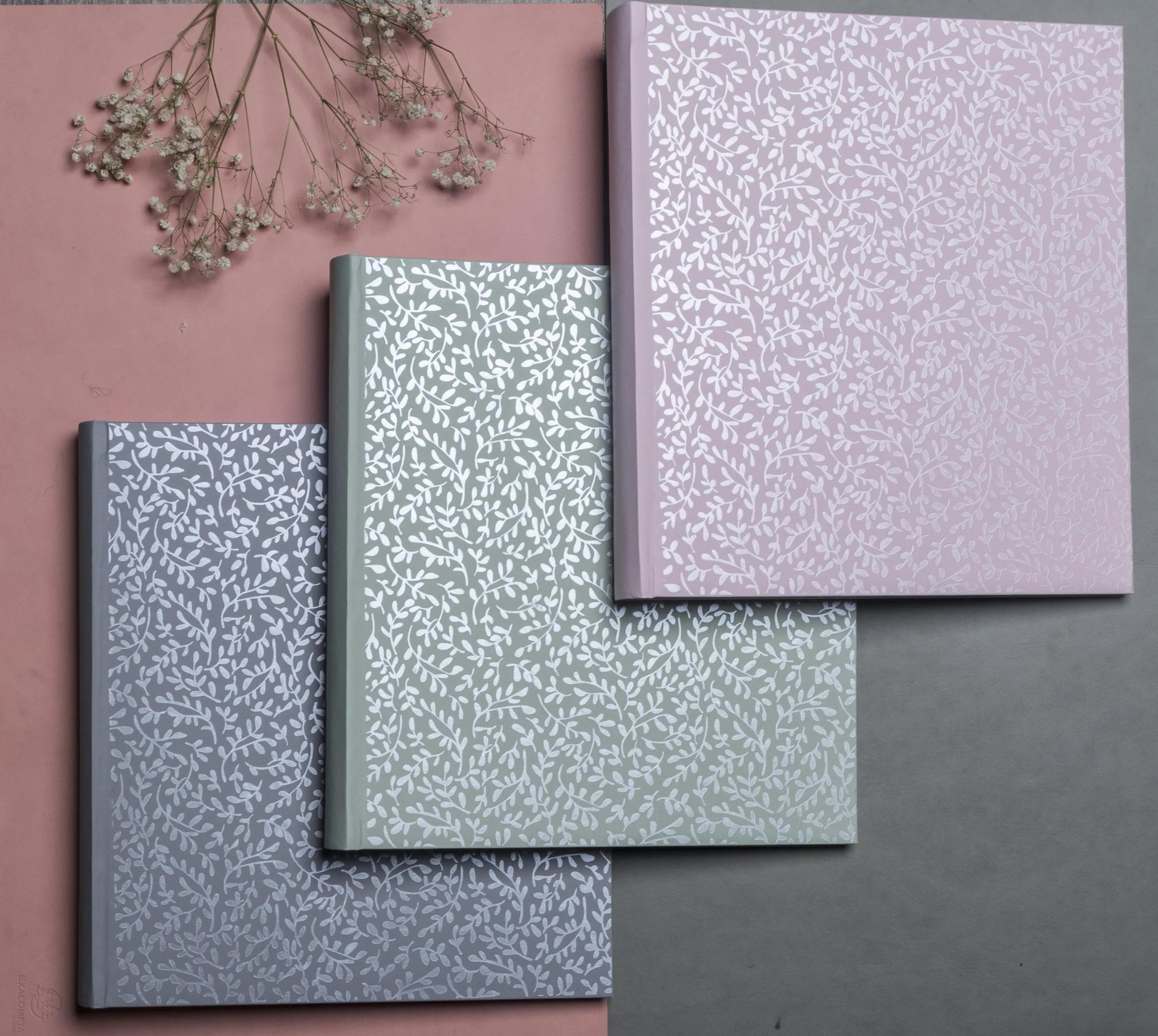 Tres cuadernos con estampado de hojas: rosa, verde y gris.