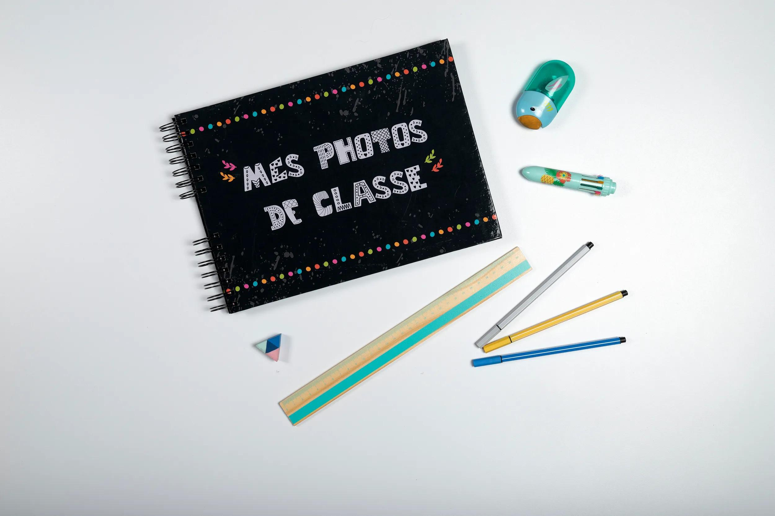 Un cuaderno negro con puntos de colores, bolígrafos, regla y goma de borrar.