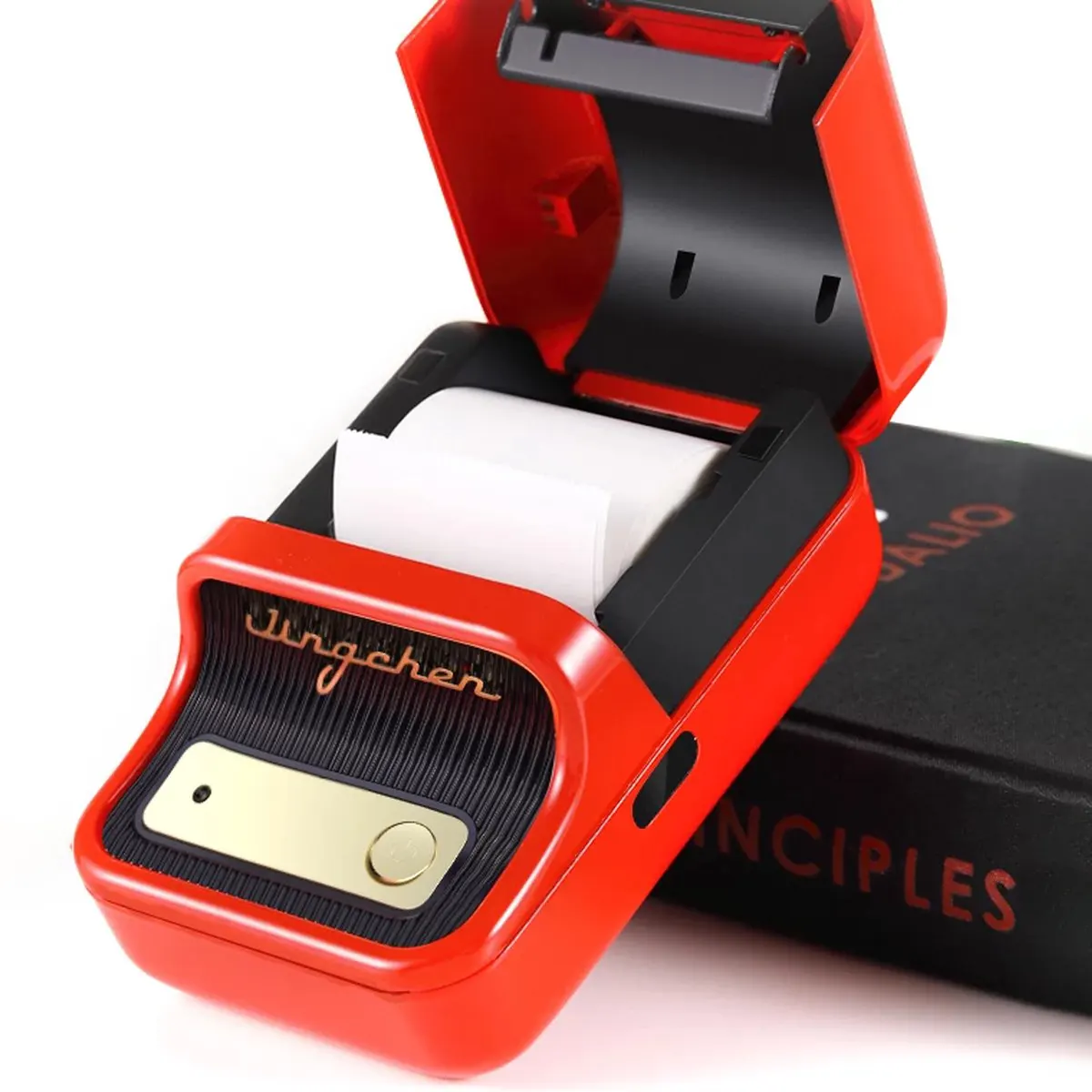 Czerwona drukarka z otwartą pokrywą, obok czarnej książki.