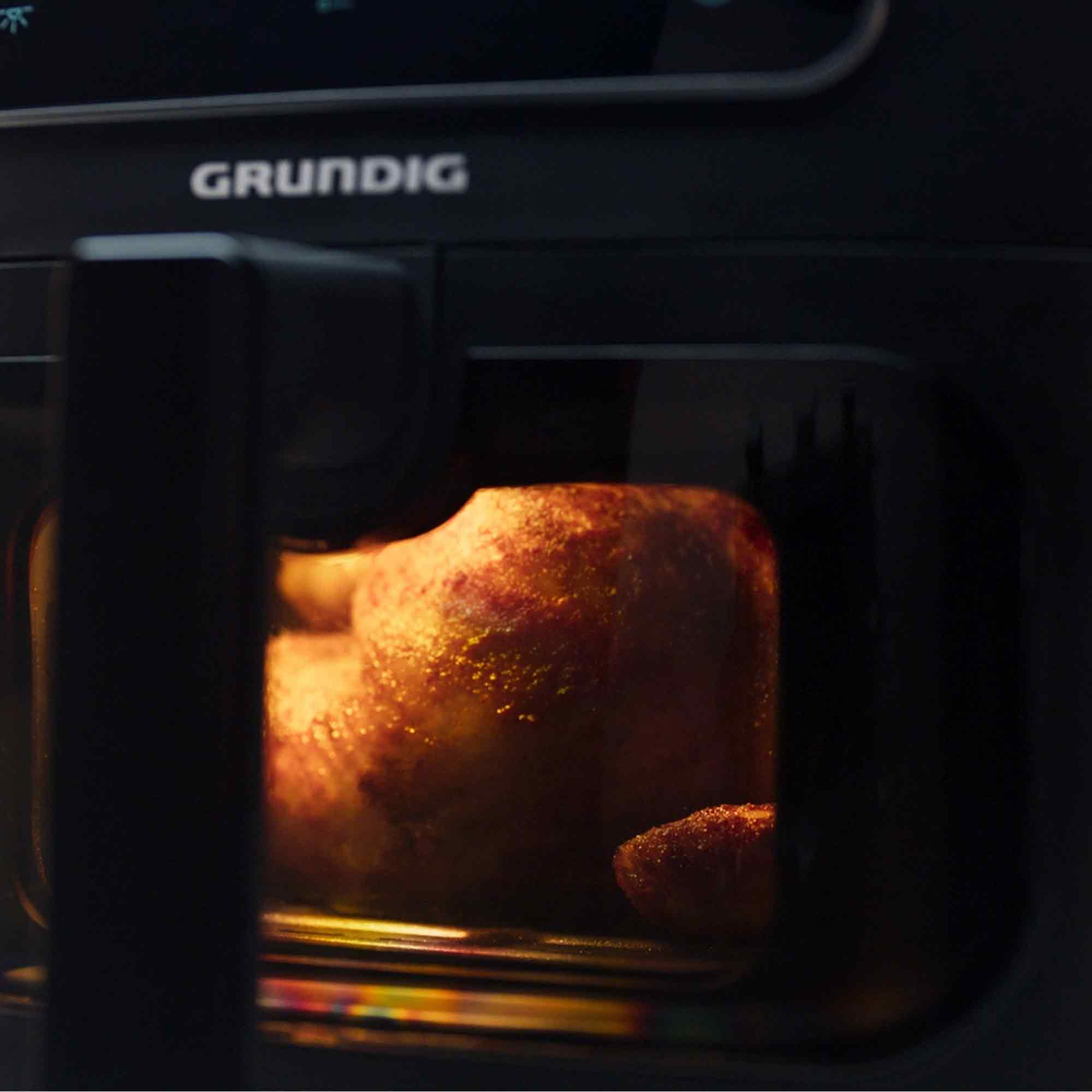 Złocisty kurczak piecze się w czarnej frytkownicy beztłuszczowej GRUNDIG.