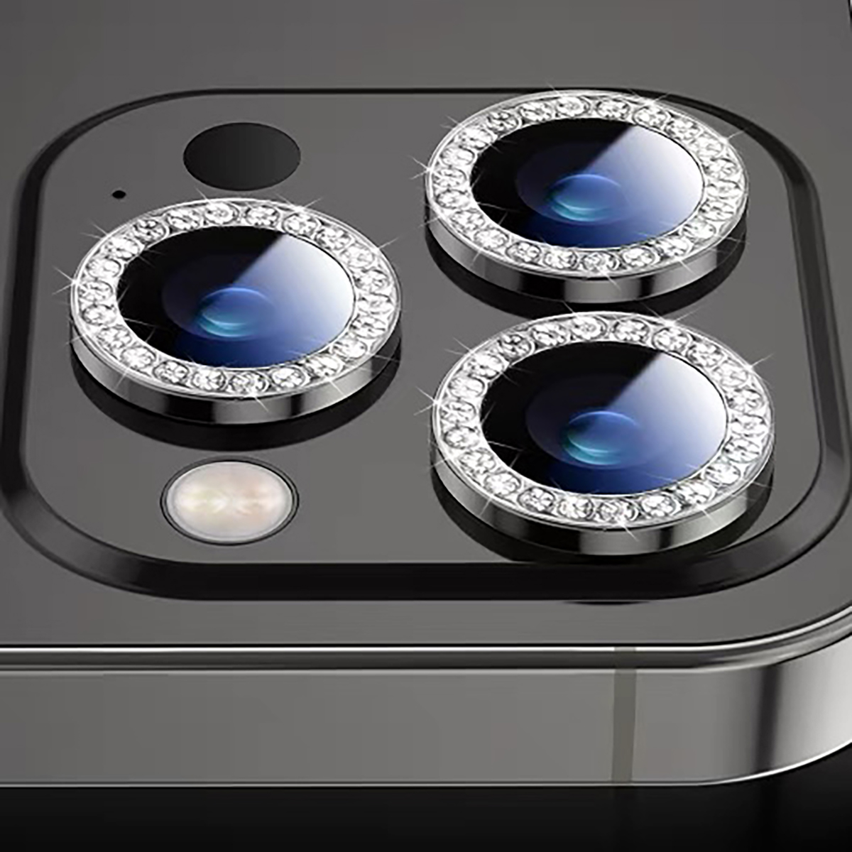 Drie met strass bezette cameralenzen op een donkere smartphonebehuizing.