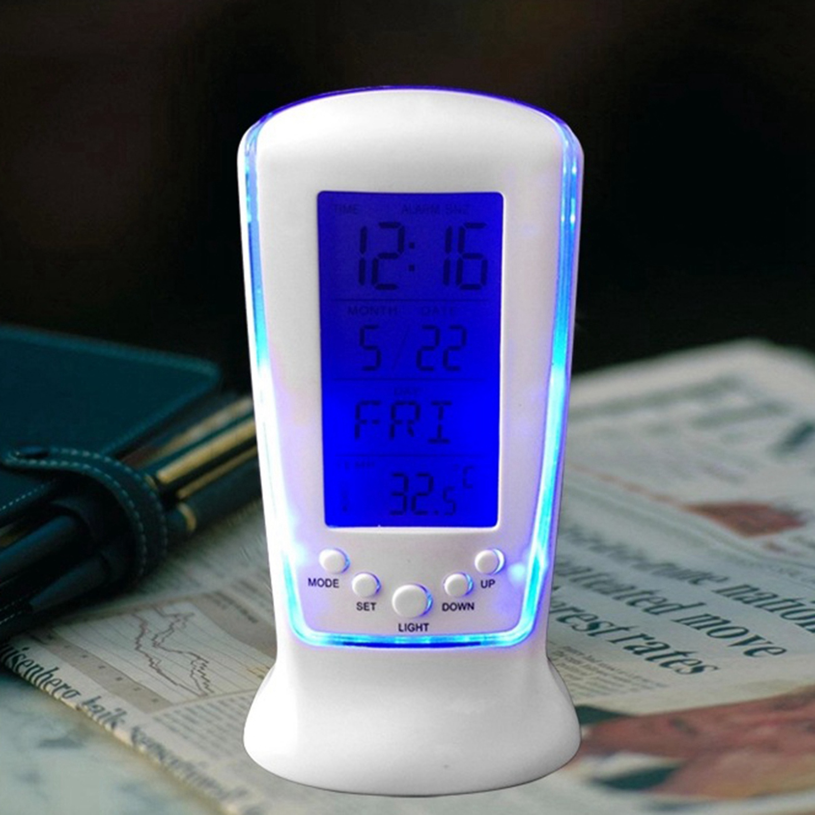 Ein weißer Digitalwecker zeigt 12:16 Uhr, 5/22, Freitag und 32,5°C an.