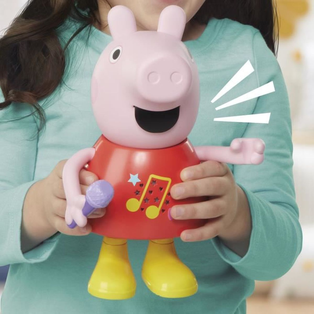 Ein rosa Schweinchen-Spielzeug mit Mikrofon in einer roten Kleidung, gehalten von Kinderhänden.