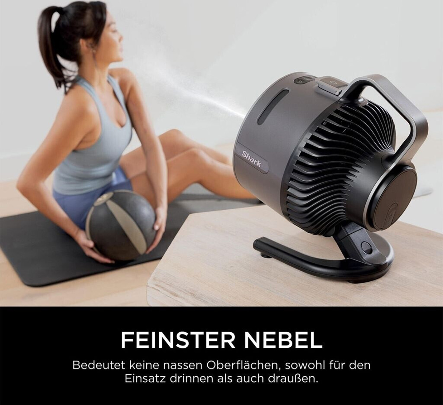 A woman exercises with a medicine ball as a misting fan cools her.